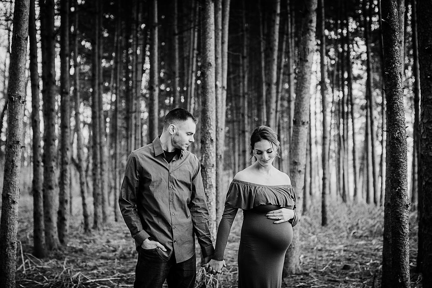  Photo of a young couple standing in a pine forest and the woman is pregnant. 