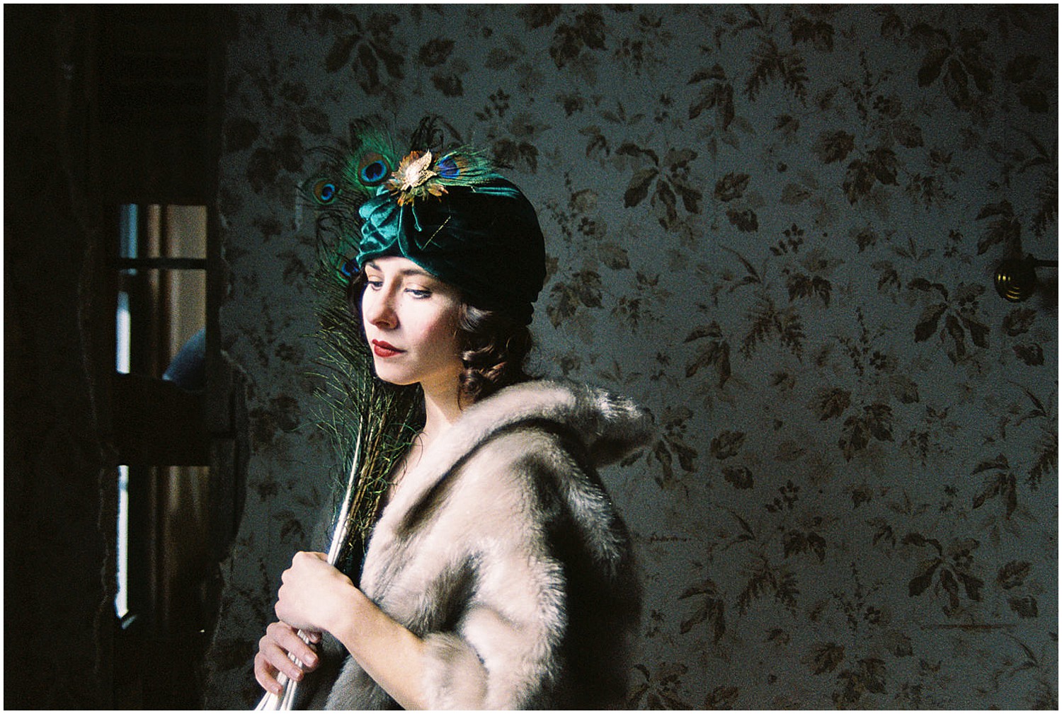  Photo of a glamorous young brunette woman wearing a green vintage flapper dress and a green velvet turban and peacock feathers. 