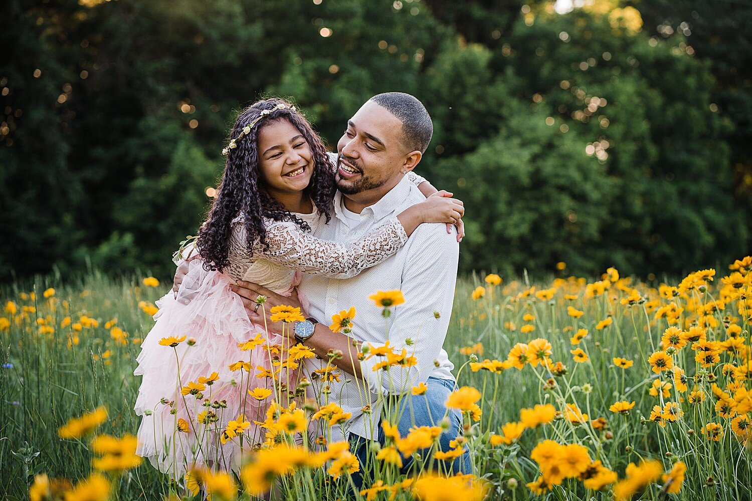  A father laughs with his daughter in a field of yellow wildflowers 