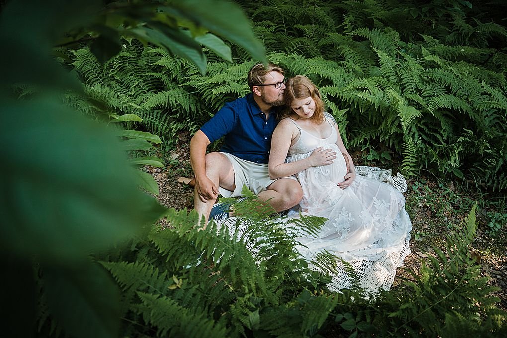 a couple sitting in a forest of ferns