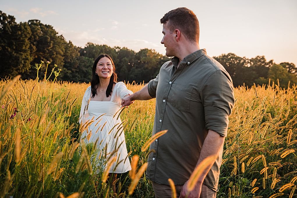 couple walks in a golden field at sunset