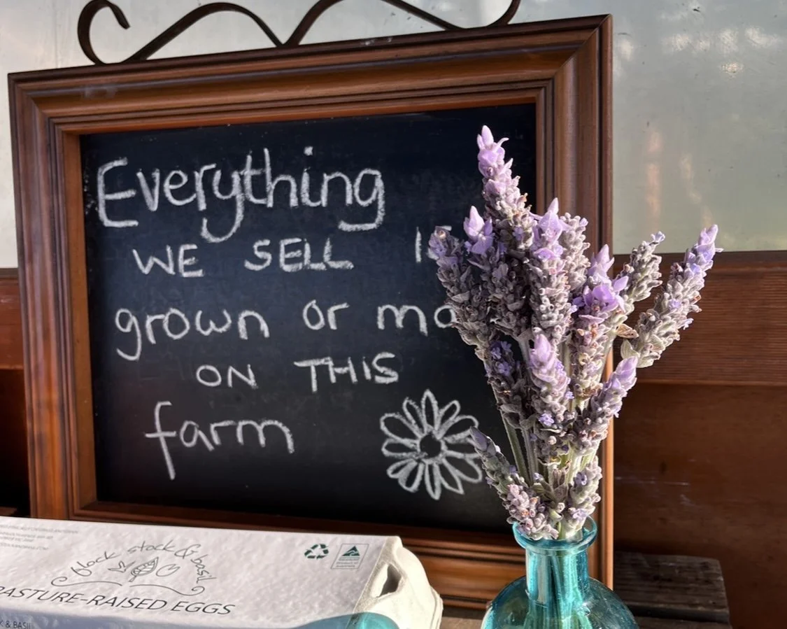 Lavender flowers with a chalkboard saying "everything we sell is grown or made on this farm"