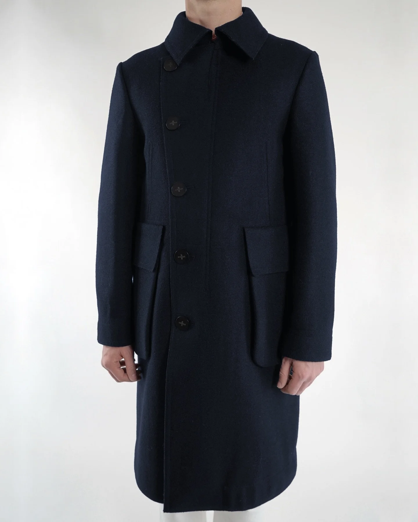 Designed with the emblematic Austrian #Loden.
A reinterpretation of the classic loden #coat, with details from the world of #tailoring and references to military clothing. The oversize loden coat is now available in navy, black and dark grey. In stor