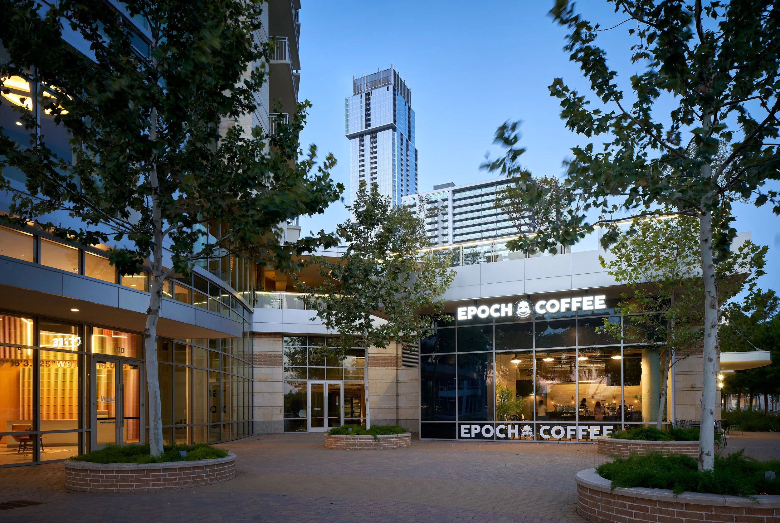 Epoch Park Tower | architecture, interiors The design of Epoch Park Tower gives a subtle nod to the name of the brand, meaning a distinct period in time. Instead of defining a particular time period, the passage of time is considered as a design element; we used materials that get better with age and utilize the movement of the sun to create dynamic, always changing patterns. Greenery, sunlight, and breeze are as much a part of the concept realization as concrete, wood, and steel. Because of the nature of the site, we were able to create one volume that is an extension of the outside - acting like a greenhouse- and another volume that contrasts the greenery through the use of reclaimed wood, concrete, and steel to give a rougher, more aged feel. A blackened and rusted steel bar is a central focal point that draws people around it and links the volumes together. Client: Epoch Coffee Location: Austin, Texas Size: 1,950 square feet