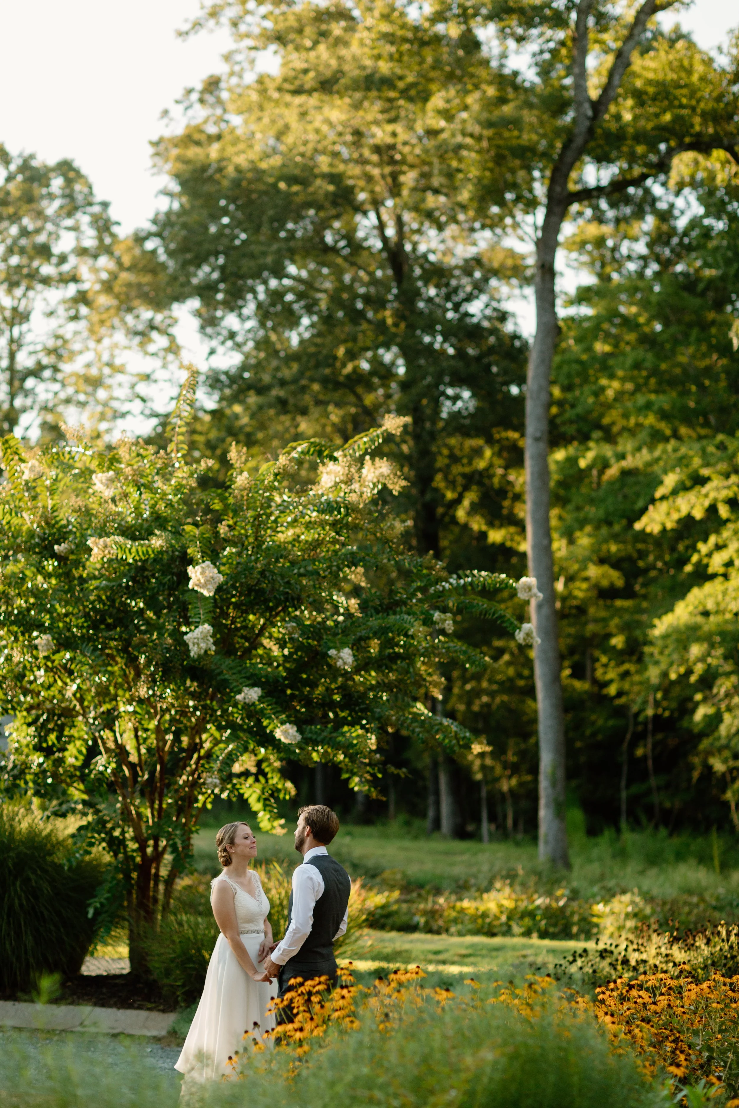 Couple standing in garden surrounded by flowers and trees at The Barn of Chapel Hill at Wild Flora Farm in Chapel Hill North Carolina