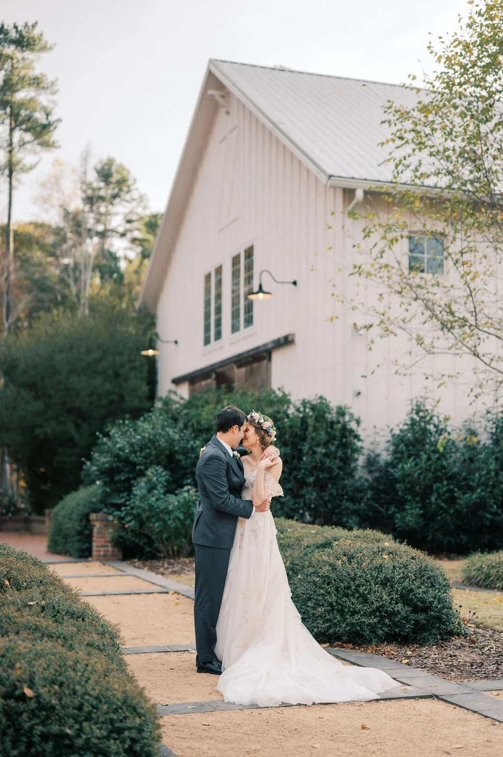 Bride and groom embracing on the garden path outside The Barn of Chapel Hill in North Carolina