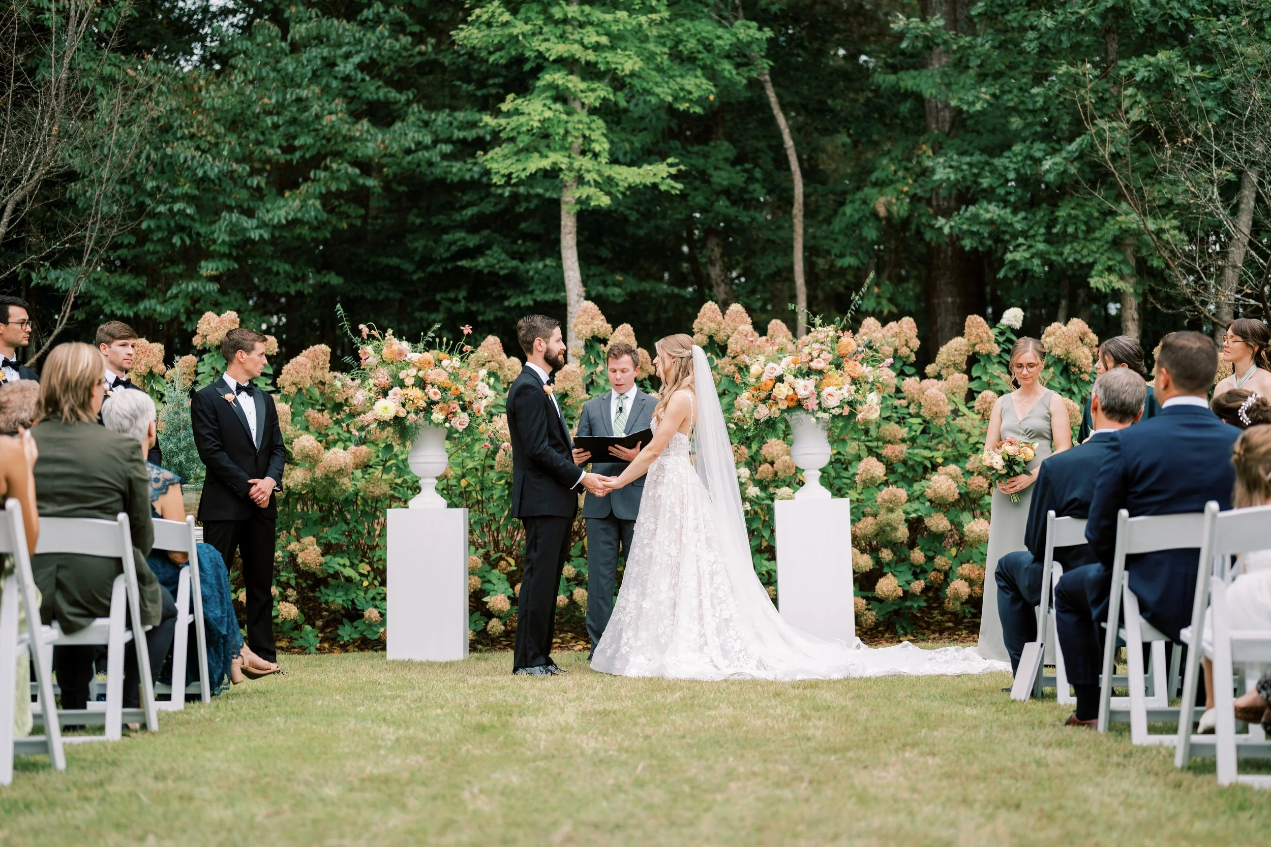 Outdoor garden wedding ceremony at The Barn of Chapel Hill surrounded by hydrangeas and summer flowers
