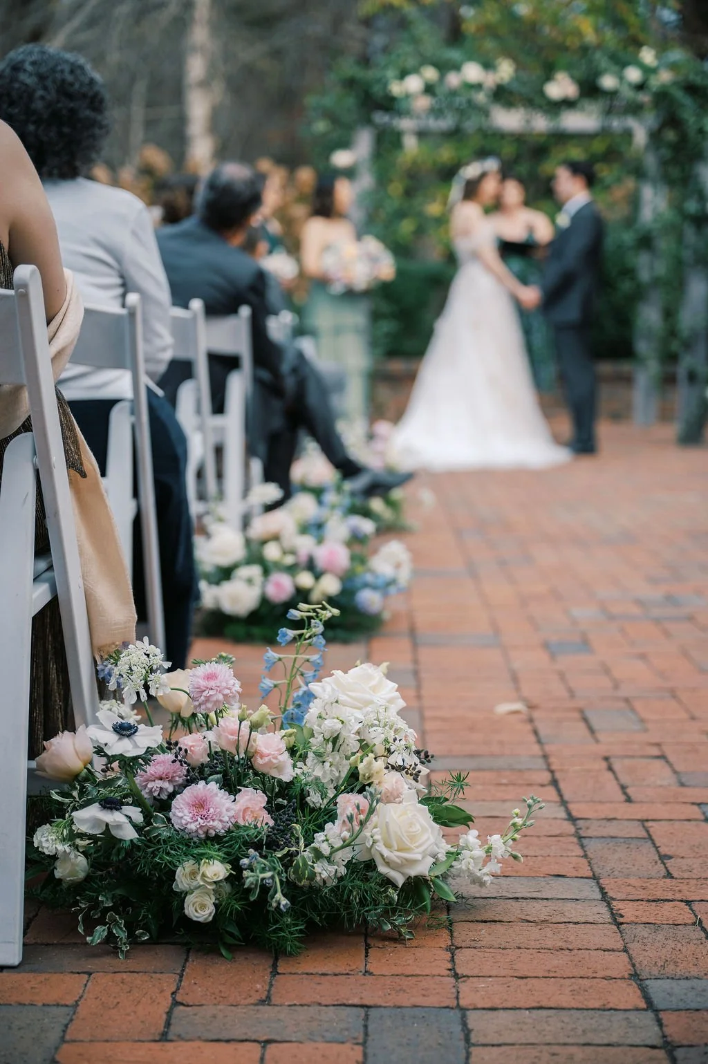Bride and groom exchanging vows during a garden ceremony at The Barn of Chapel Hill with floral aisle arrangements