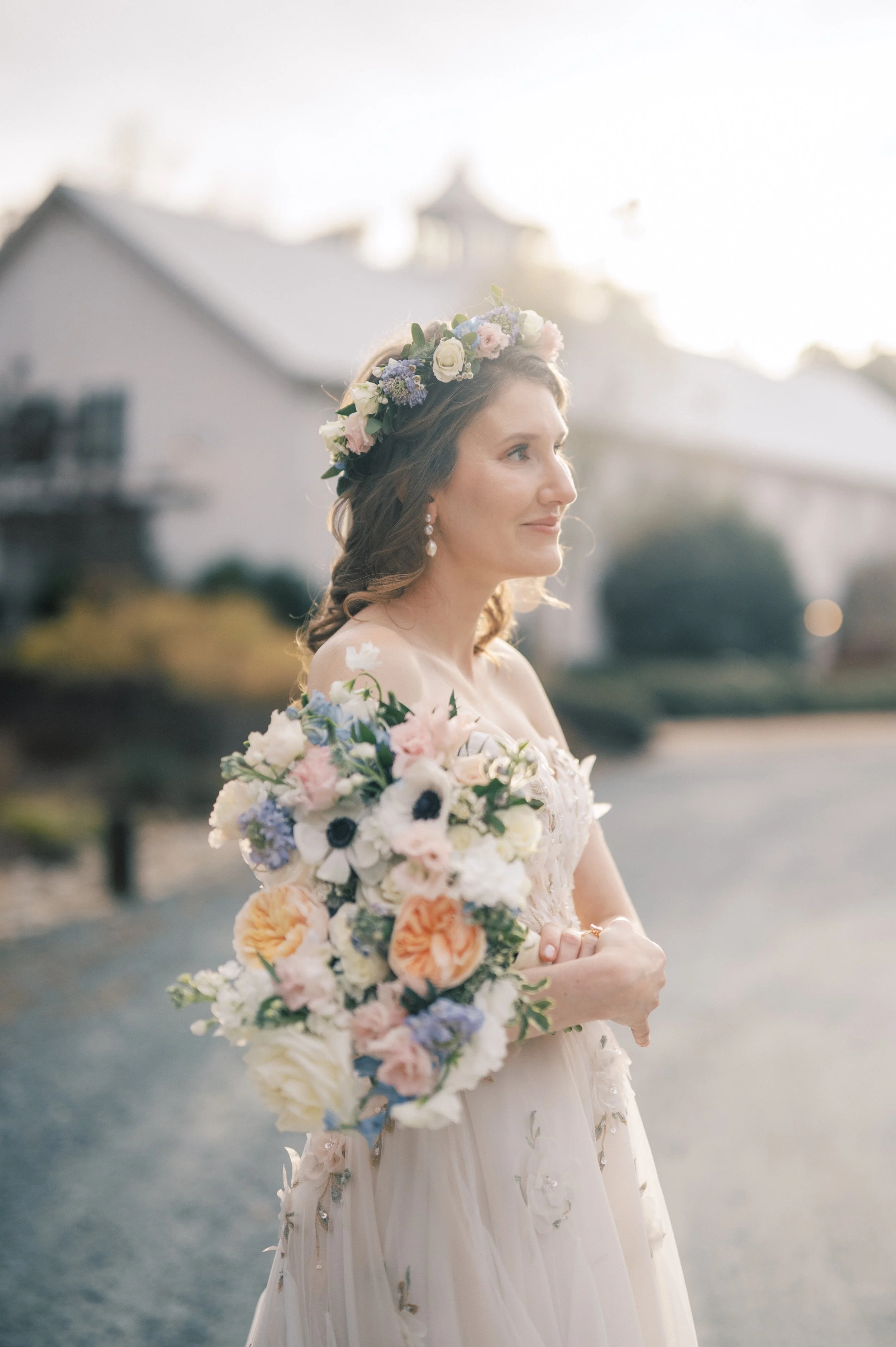 Bride holding a garden-style bouquet outside The Barn of Chapel Hill in North Carolina with the barn in the background