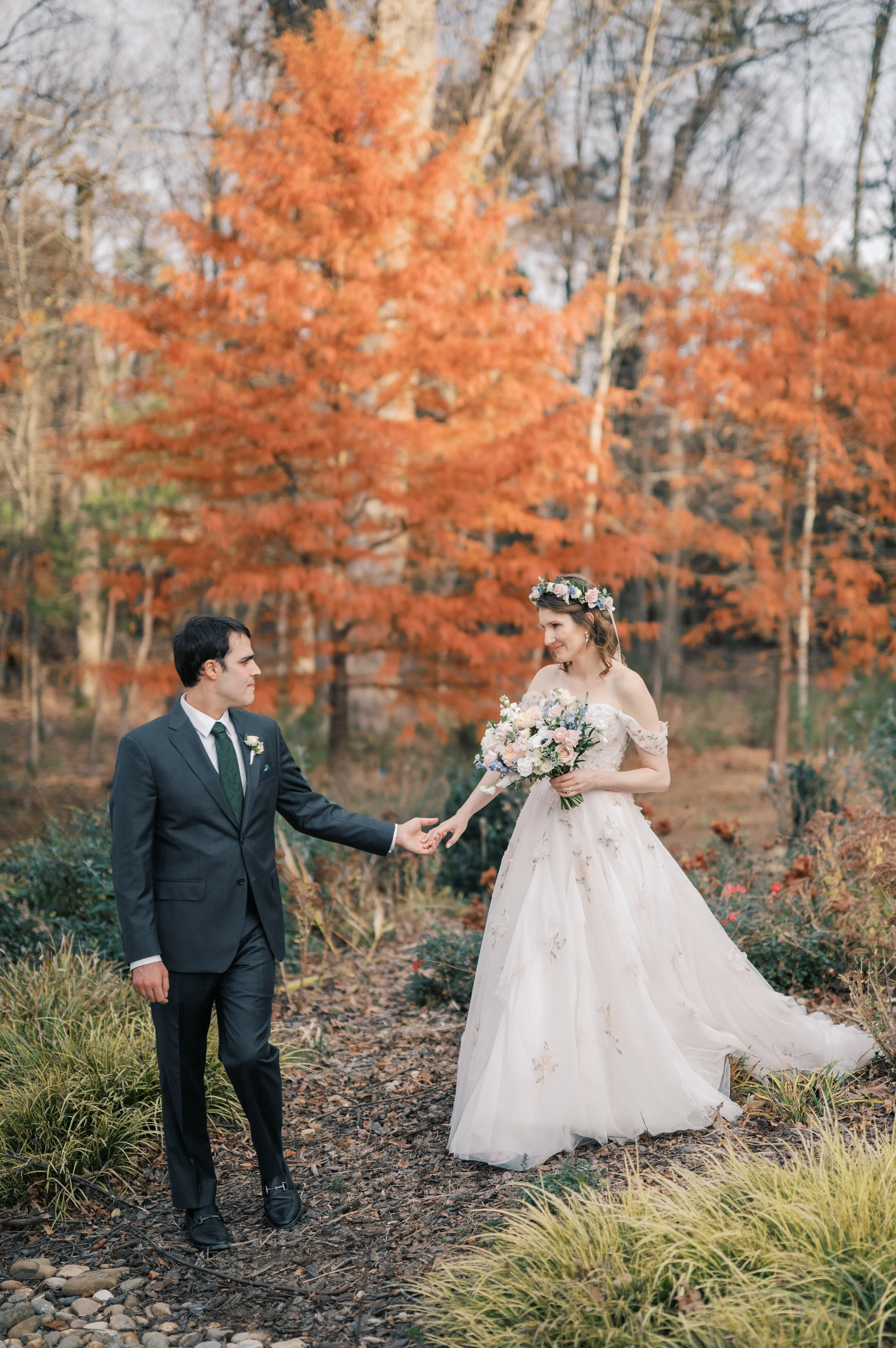 Bride and groom walking through the garden with fall foliage at The Barn of Chapel Hill in  North Carolina