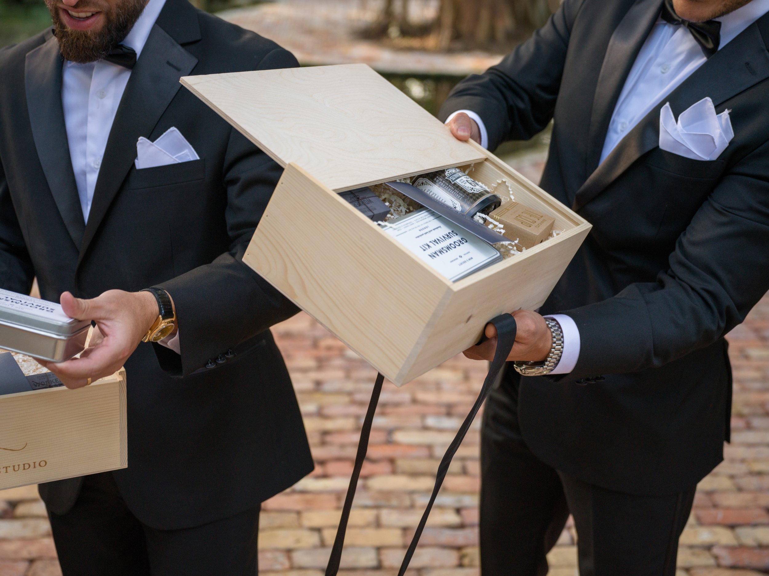 Groomsmen opening personalized luxury gift boxes at Miami wedding