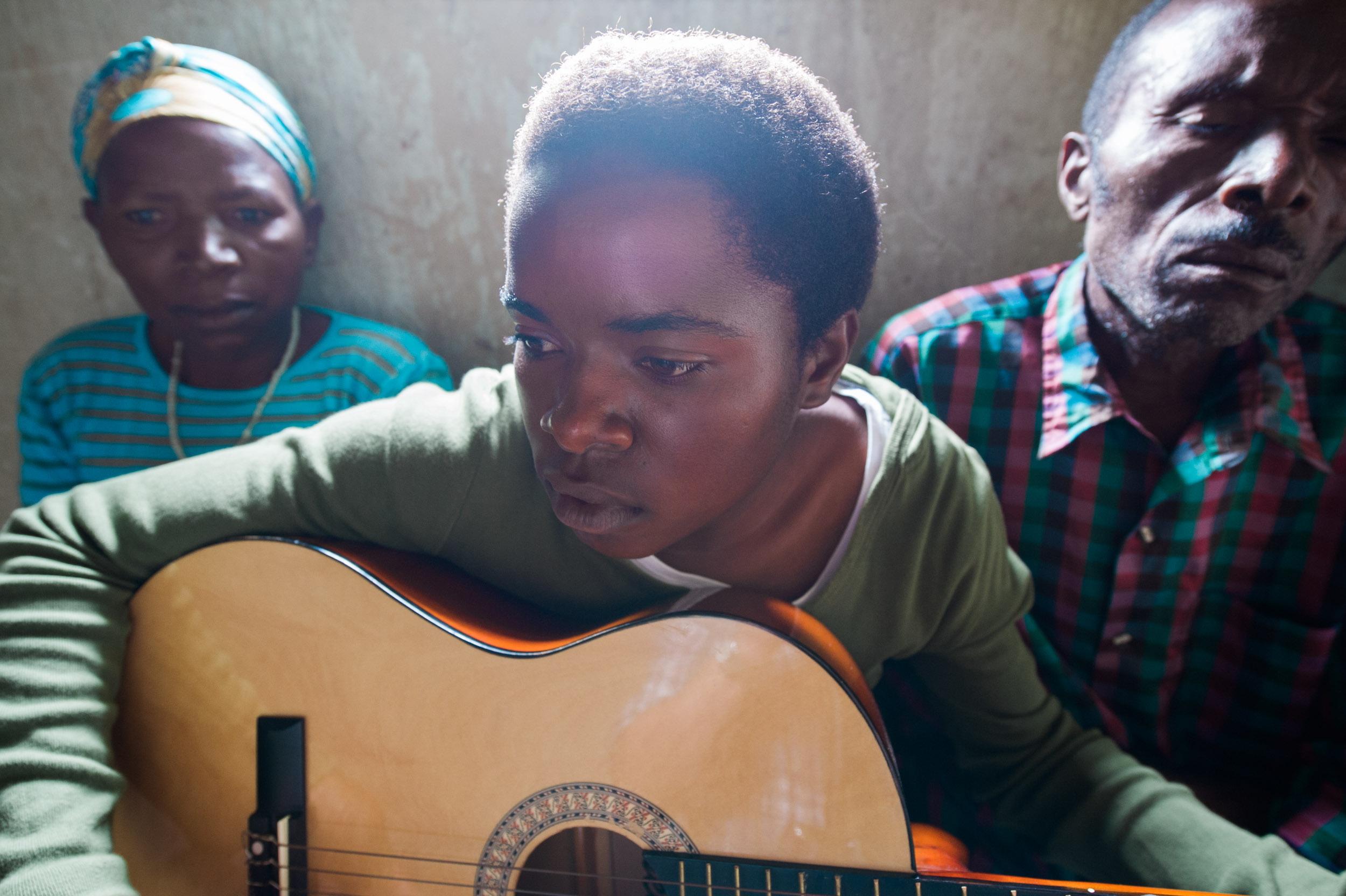  A young girl performs with her new guitar - given to her as part of Nike Foundation Girl Effect's initiative to empower Rwandan girls - as her parents look on in their mud brick hut in central Rwanda. 