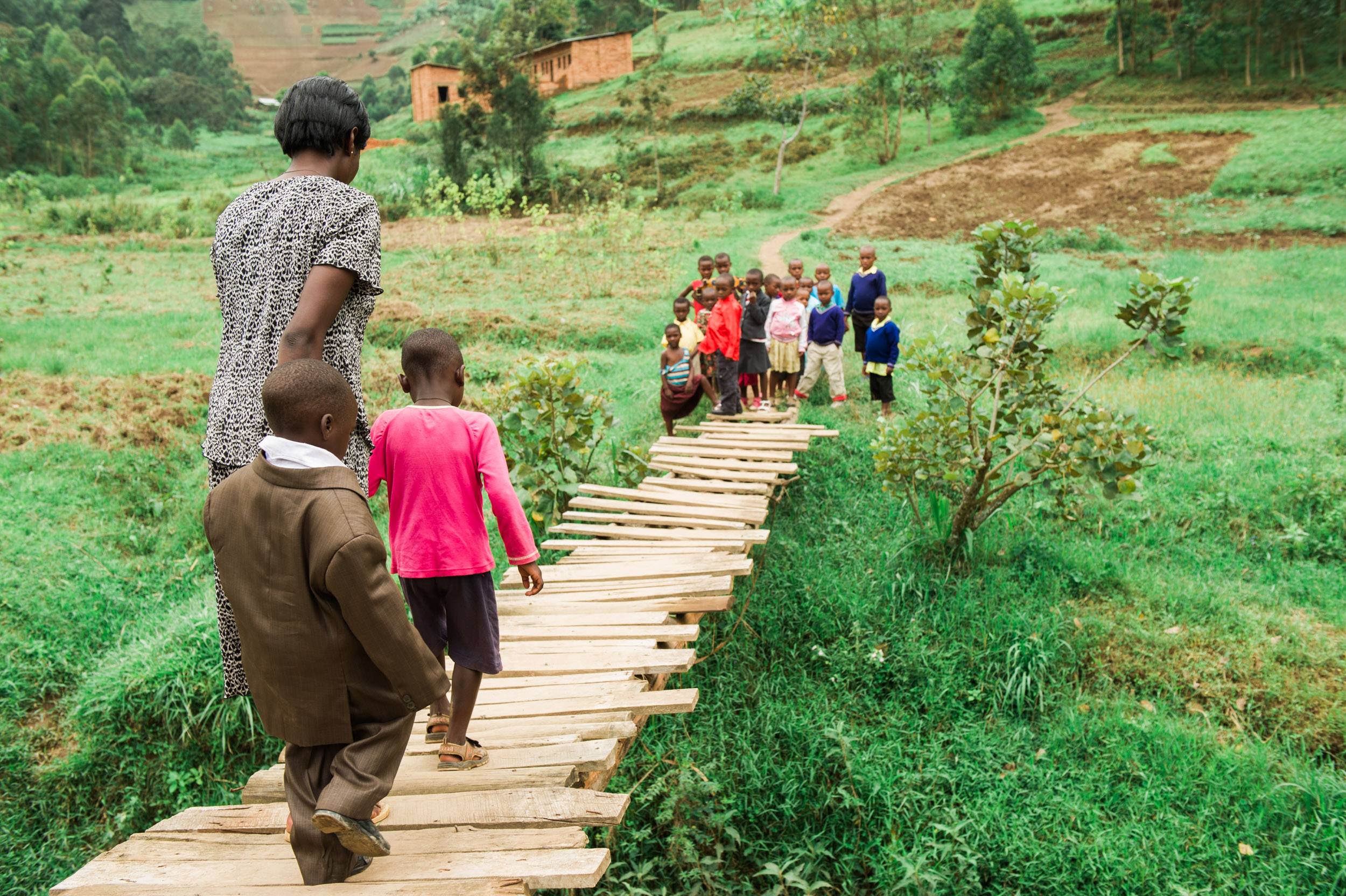  A school teacher leads her young students across a bridge toward the village's school building, in central Rwanda. 