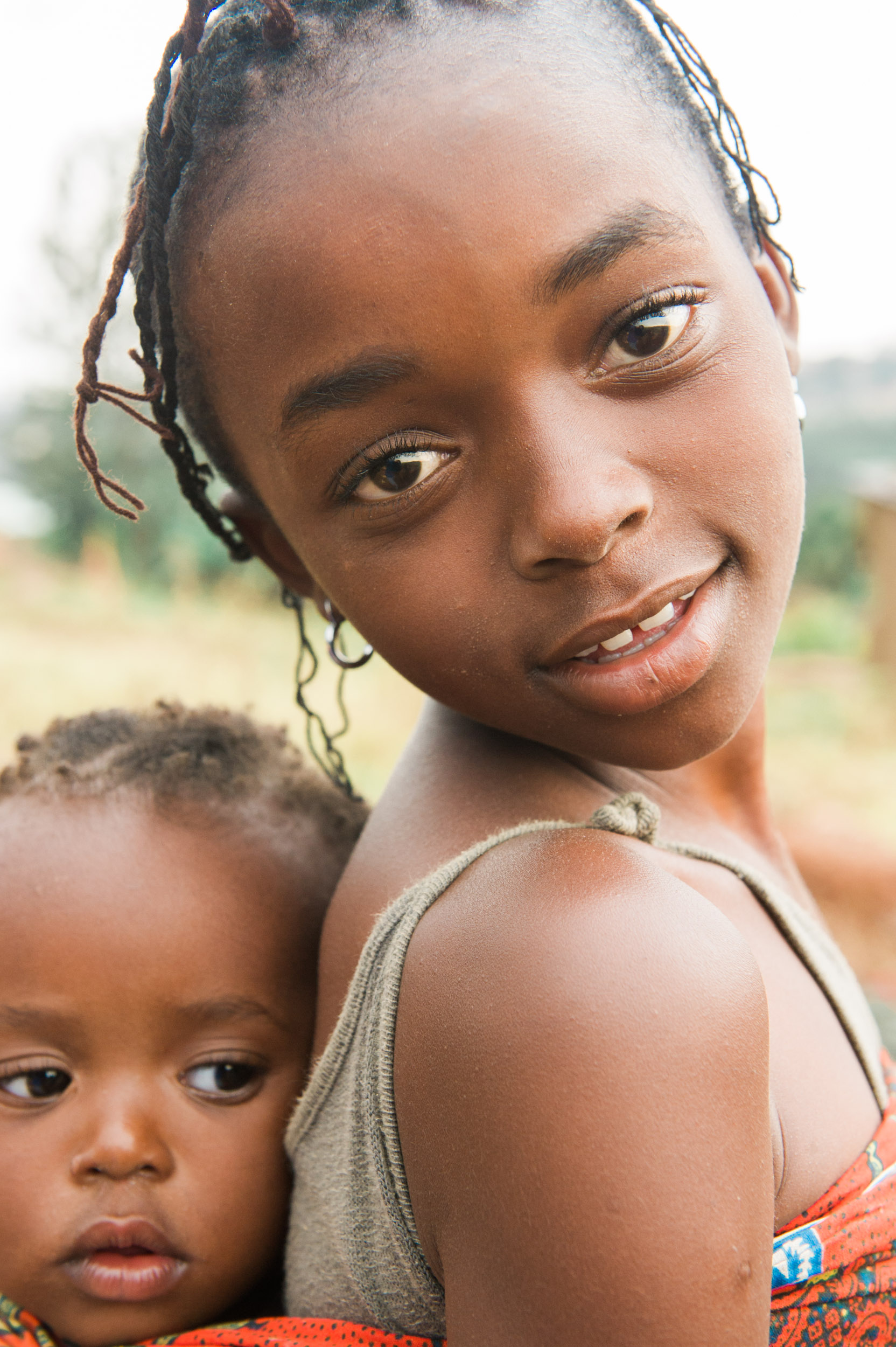  A young girl with her young brother wrapped in Rwandan cloth on her back. 