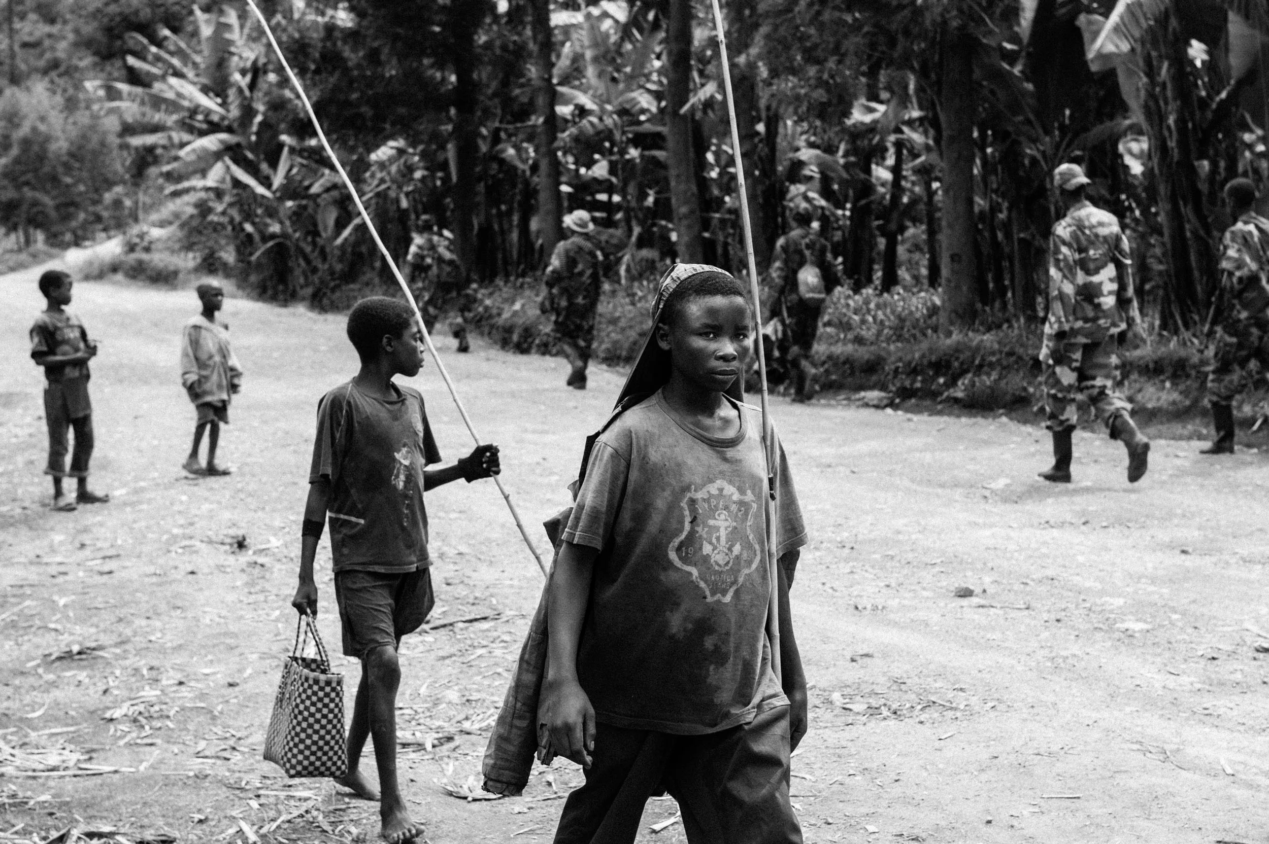  Boys carrying fishing rods pass a group of M23 rebels moving toward Lake Kivu.  