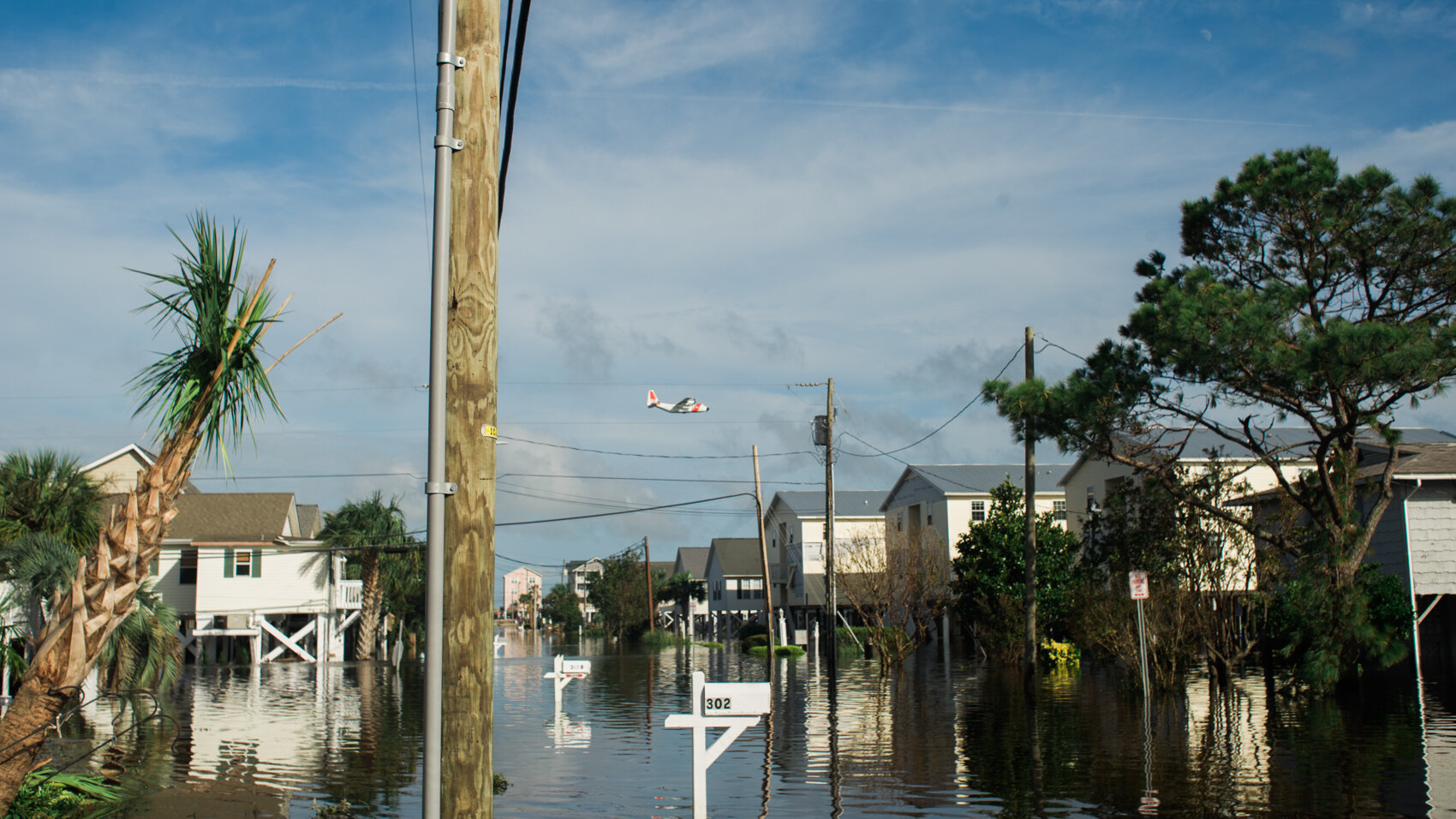  A Coast Guard cargo plane flies over Carolina Beach on Monday, September 17, 2018. Pictured is a flooded section of Atlanta Avenue and 4th Street just north of the Carolina Beach Lake, three days after Hurricane Florence struck the region.  (See the