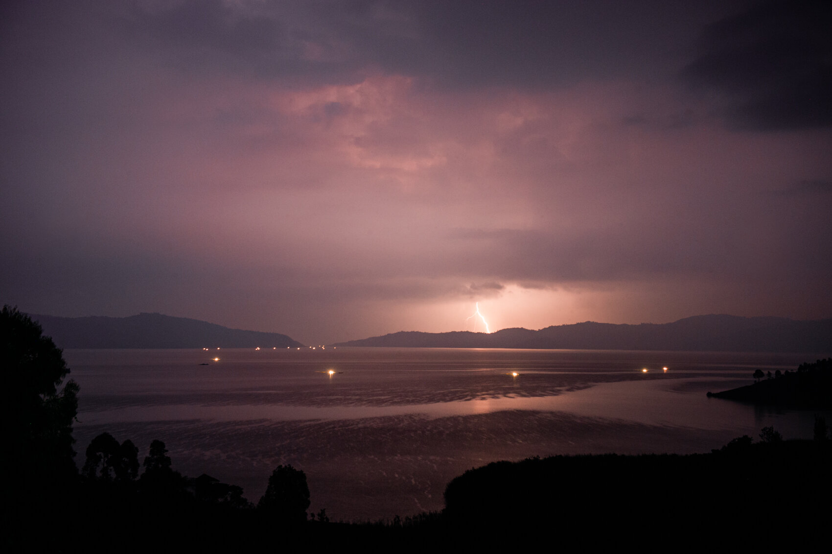 Lightning strikes as a line of fishermen snake toward Rwanda's border with the DRC.