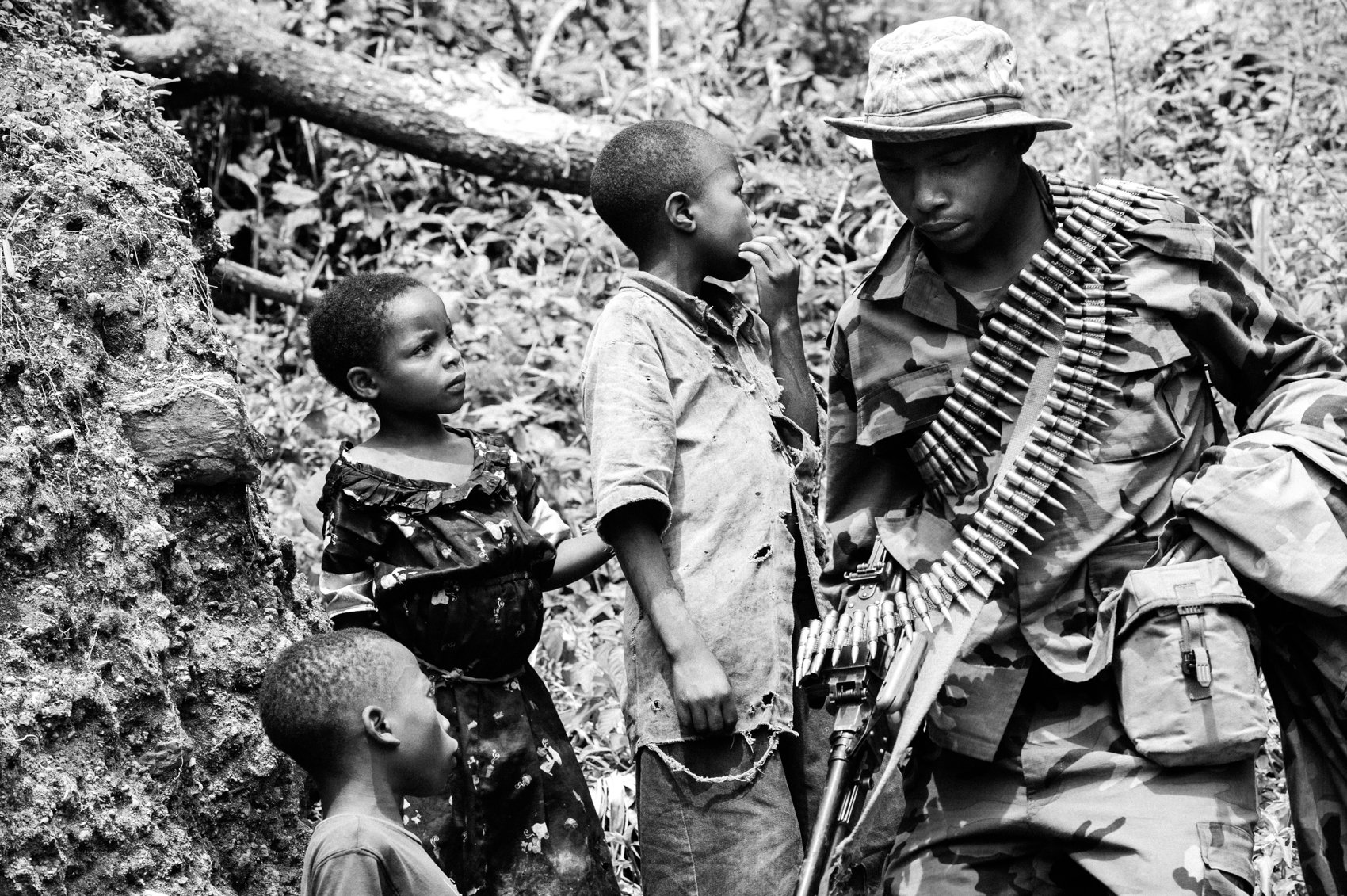  An M23 rebel walks by a group of children near Goma during the 2012 M23 Rebellion in eastern DRC. 