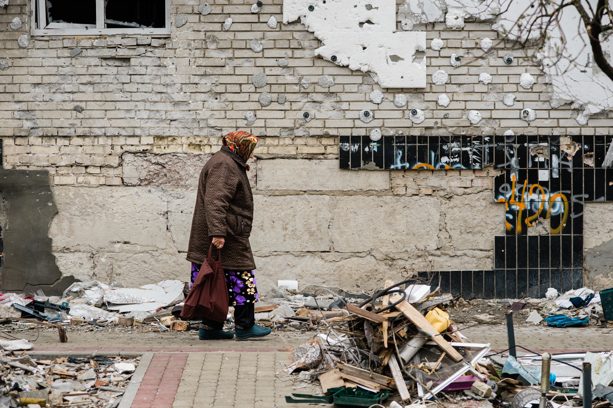  An old woman walks by the remains of a building hit by Russian missiles, Irpin, Ukraine 