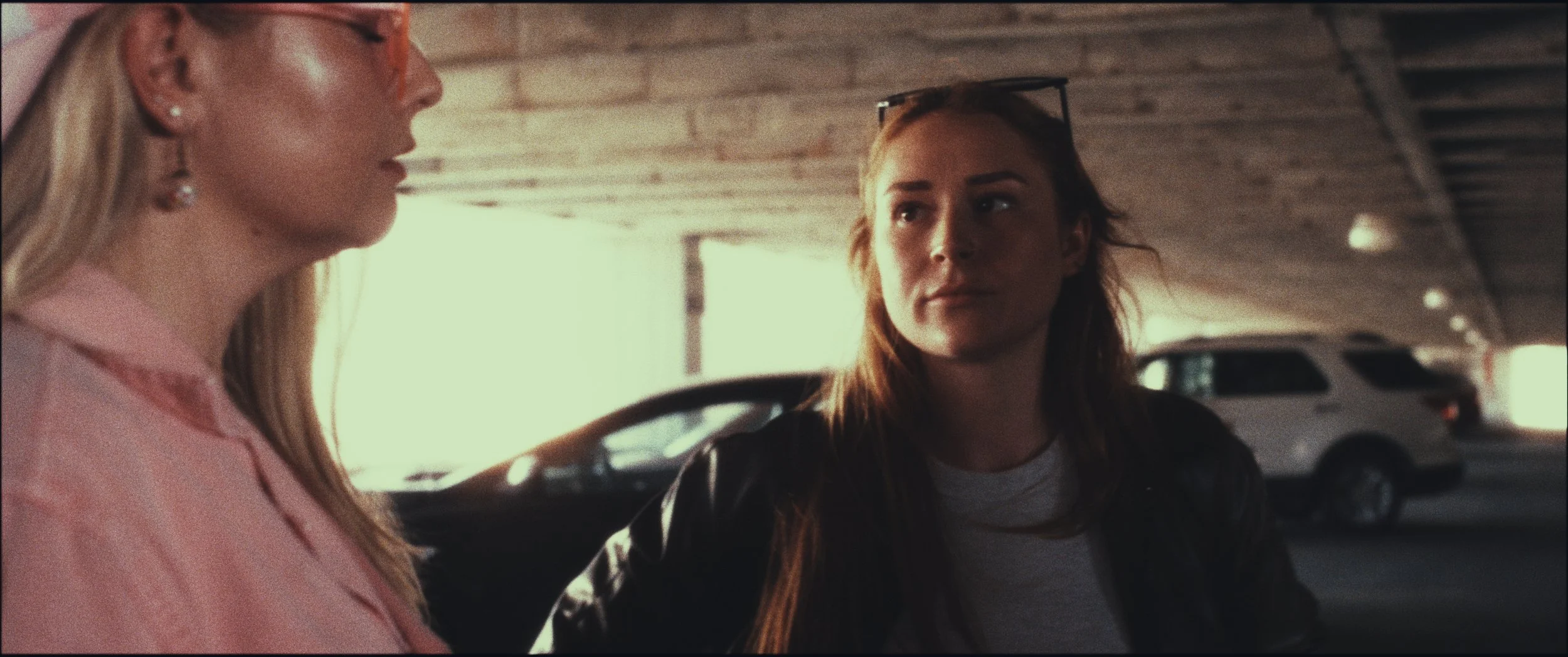 Two women facing each other in a parking garage, still from Five Finger Stakeout (2026), shot in Omaha, Nebraska by cinematographer Cole Mowery