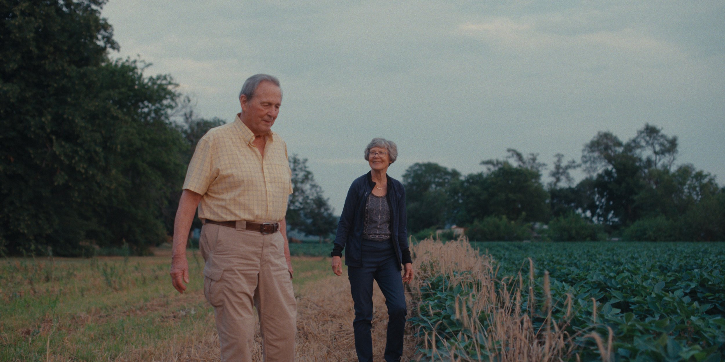 Farming couple walking beside a soybean field on an overcast evening, still from a Folsom Lake Solar commercial shot in Mills County, Iowa by director of photography Cole Mowery