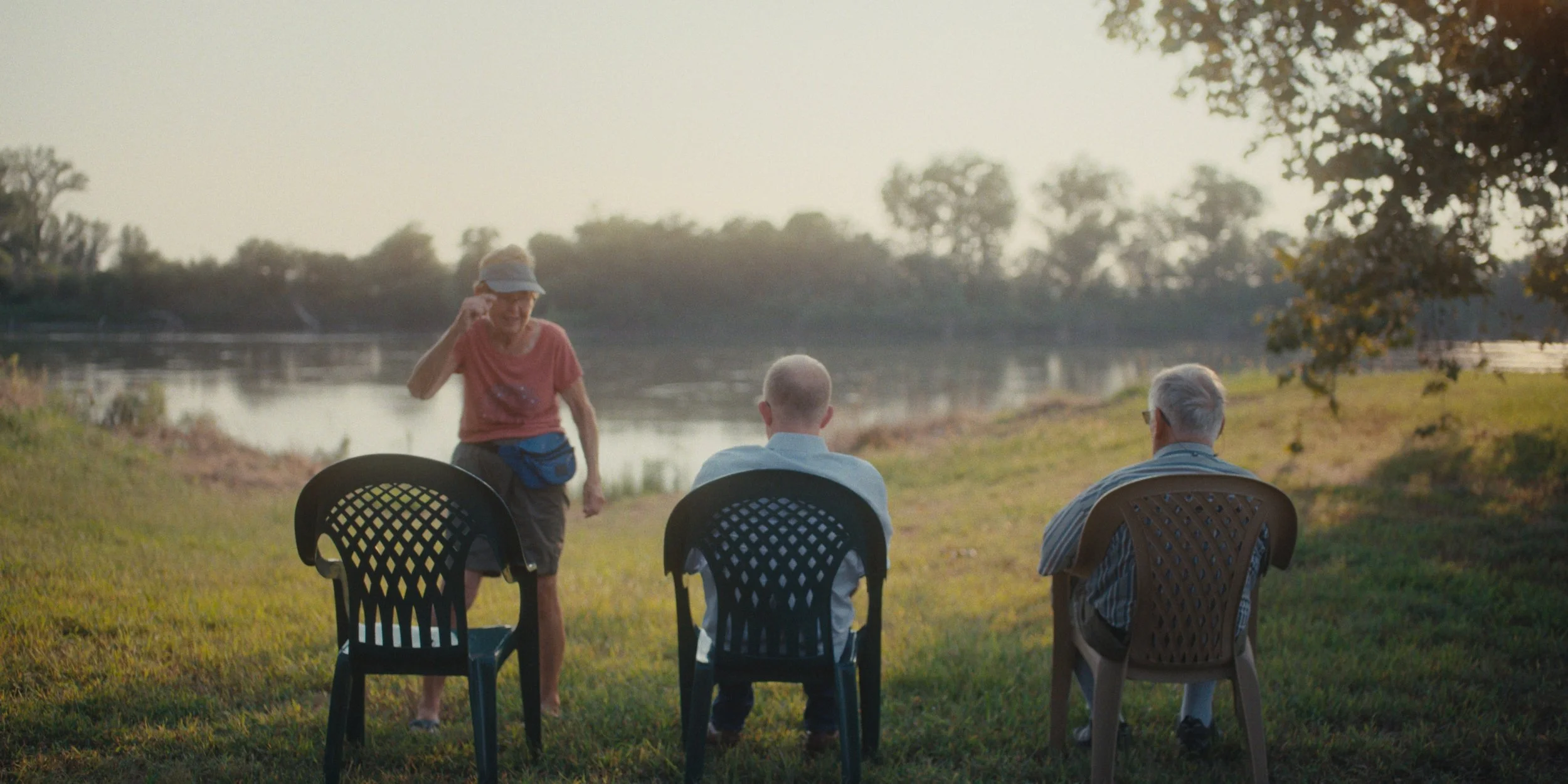 Family sitting in lawn chairs beside a pond at sunrise, still from a Folsom Lake Solar commercial shot in Mills County, Iowa by director of photography Cole Mowery