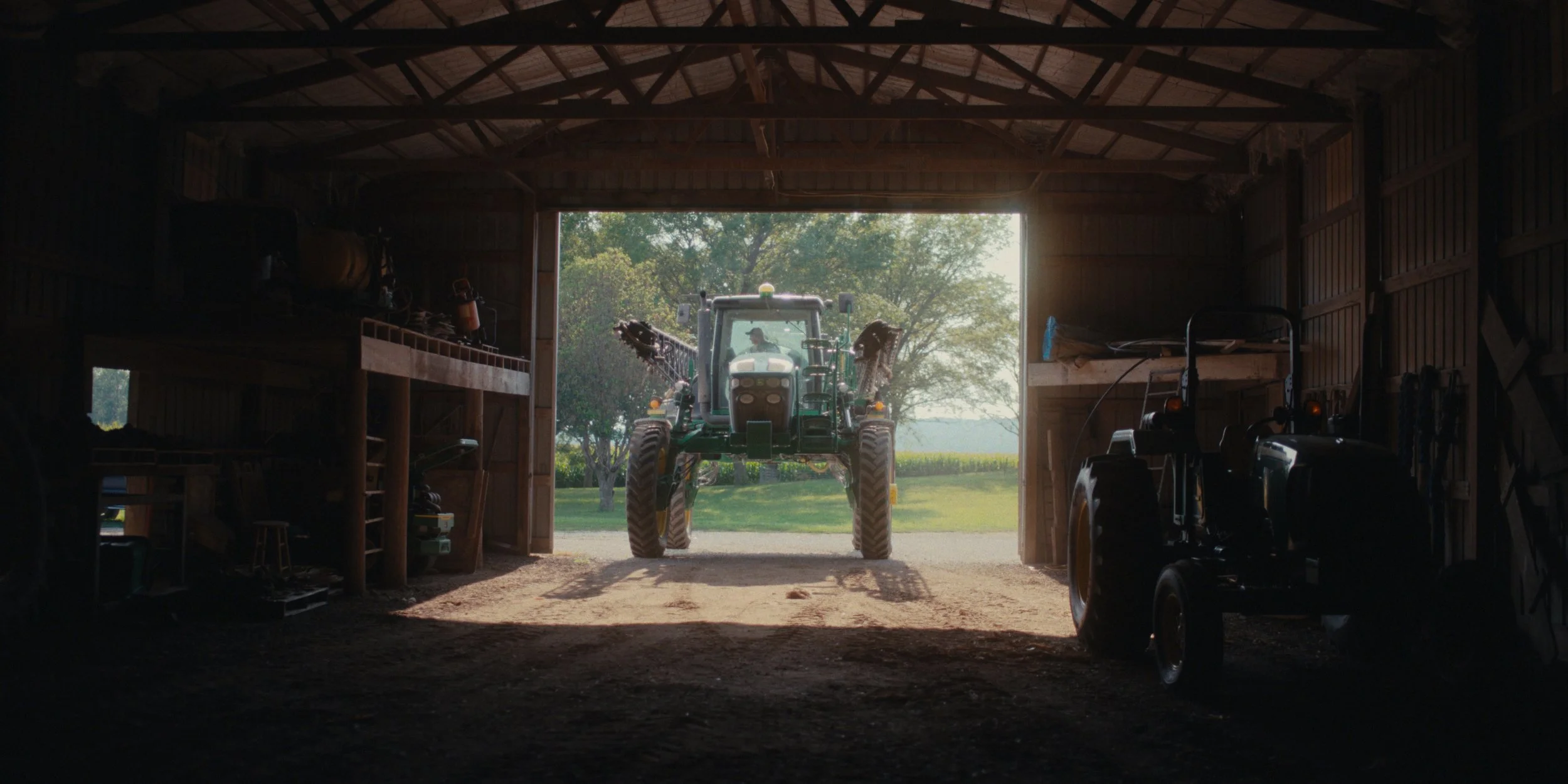 Tractor framed by the open doors of a dark machine shed, still from a Folsom Lake Solar commercial shot in Mills County, Iowa by director of photography Cole Mowery