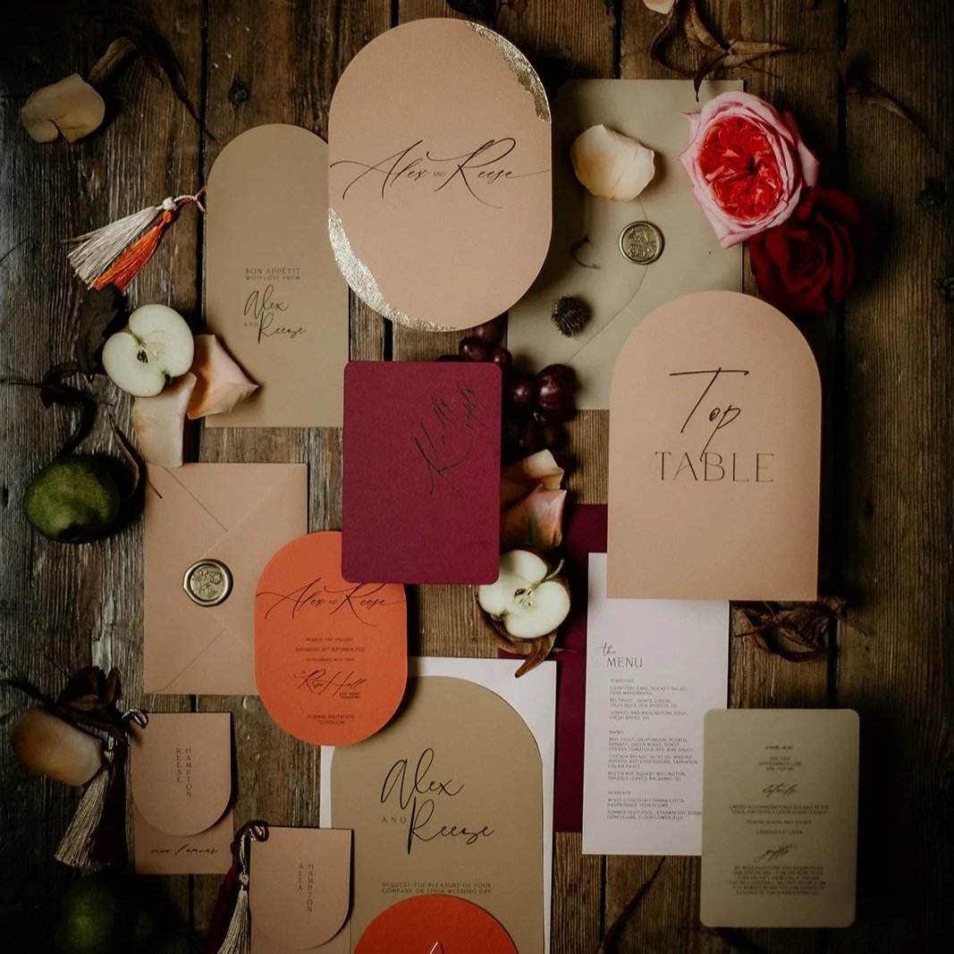 Wedding invitation stationery with floral decorations, including roses, scattered on a wooden surface.