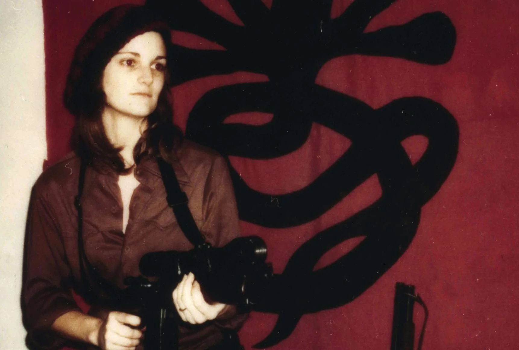 Patty Hearst posing in front of SLA banner