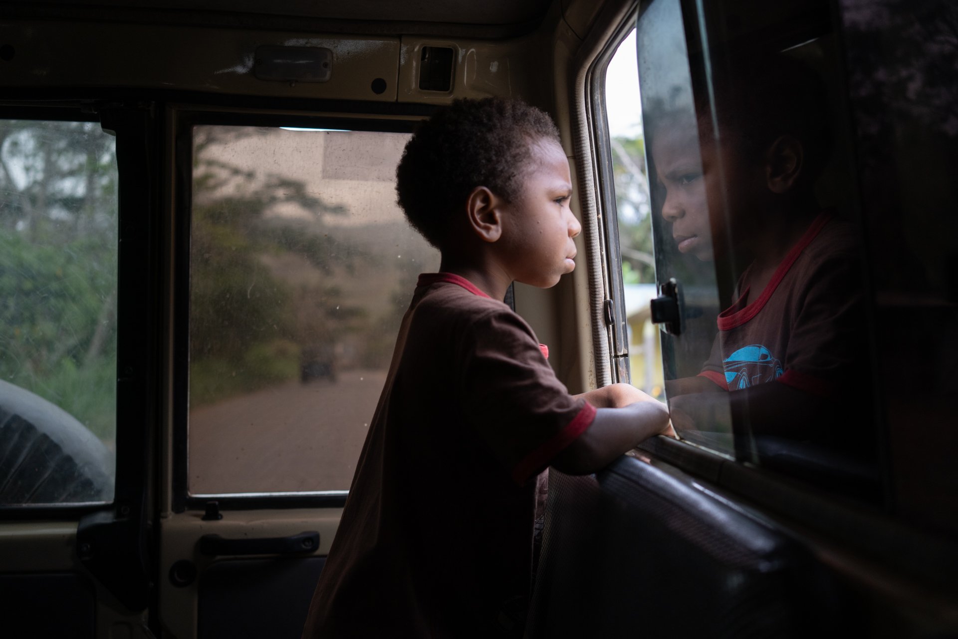  A boy looks out the window of a 4WD navigating the rough roads between Goroka and Aiyura in the Central Highlands of Papua New Guinea. August 2019. 