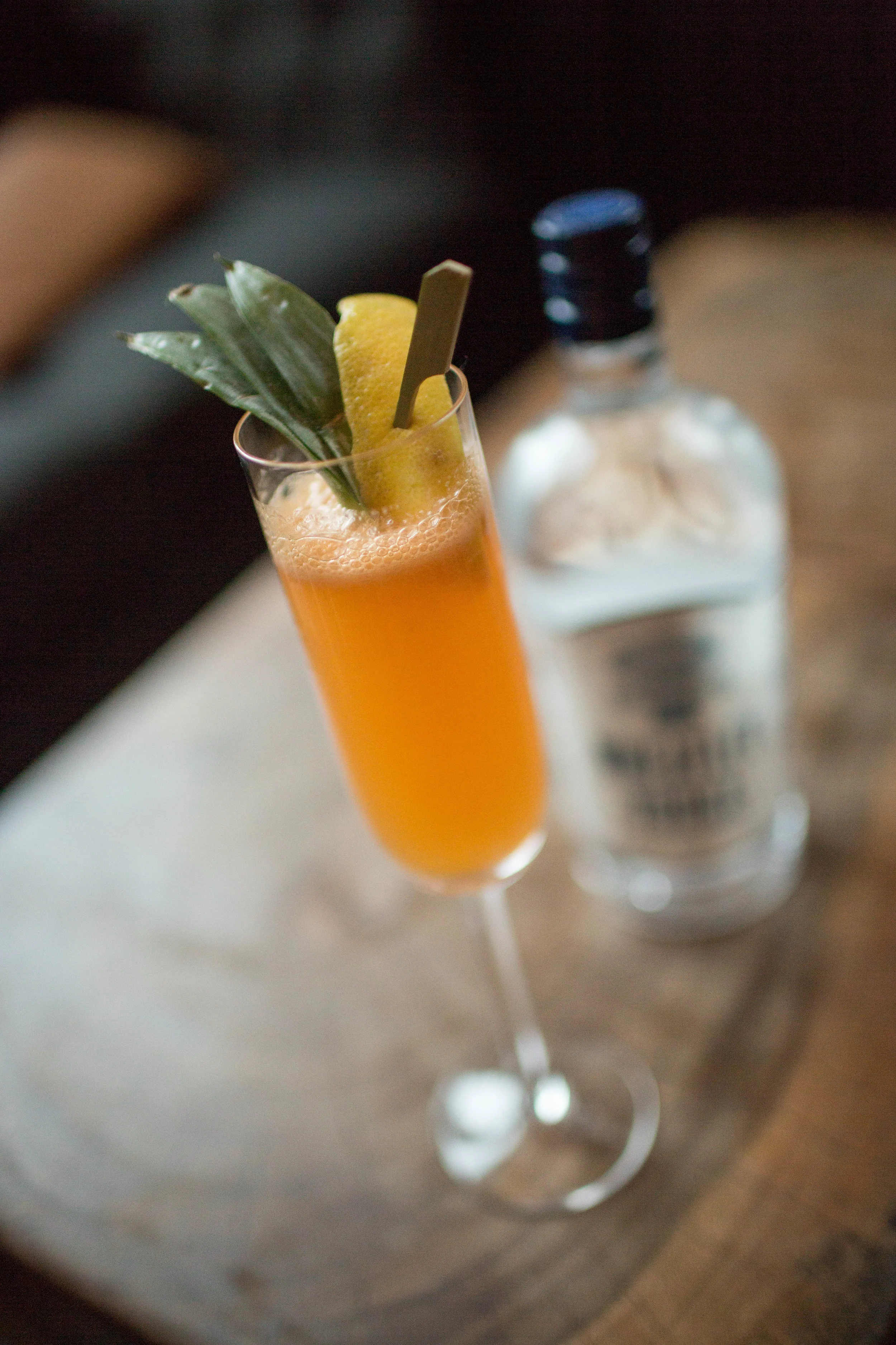Orange-colored cocktail in front of a bottle of Wheatley Vodka.