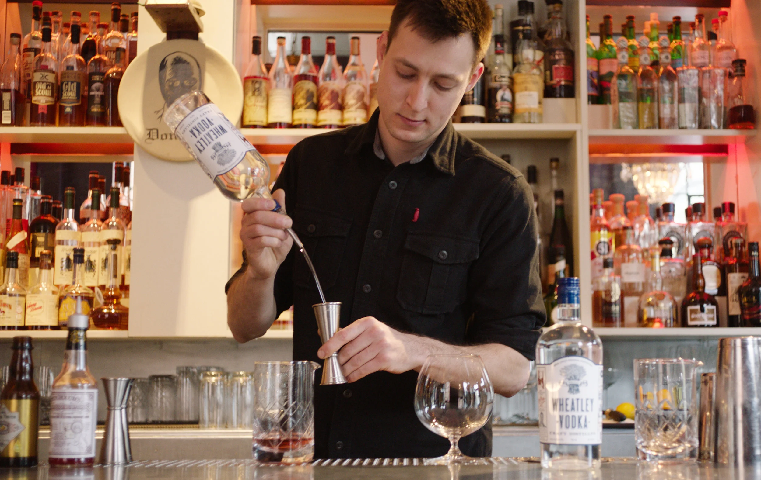 Proof on Main Bartender Greg Galganski standing behind his bar preparing a cocktail with Wheatley Vodka.