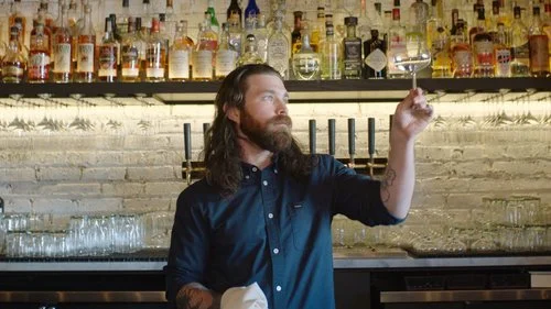Matthew Wesolik, a bartender a Clever Rabbit, standing behind his bar looking into the camera with a focused expression.
