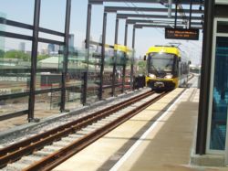 A southbound Hiawatha line car arrives at the Lake Street station with downtown Minneapolis as the backdrop.