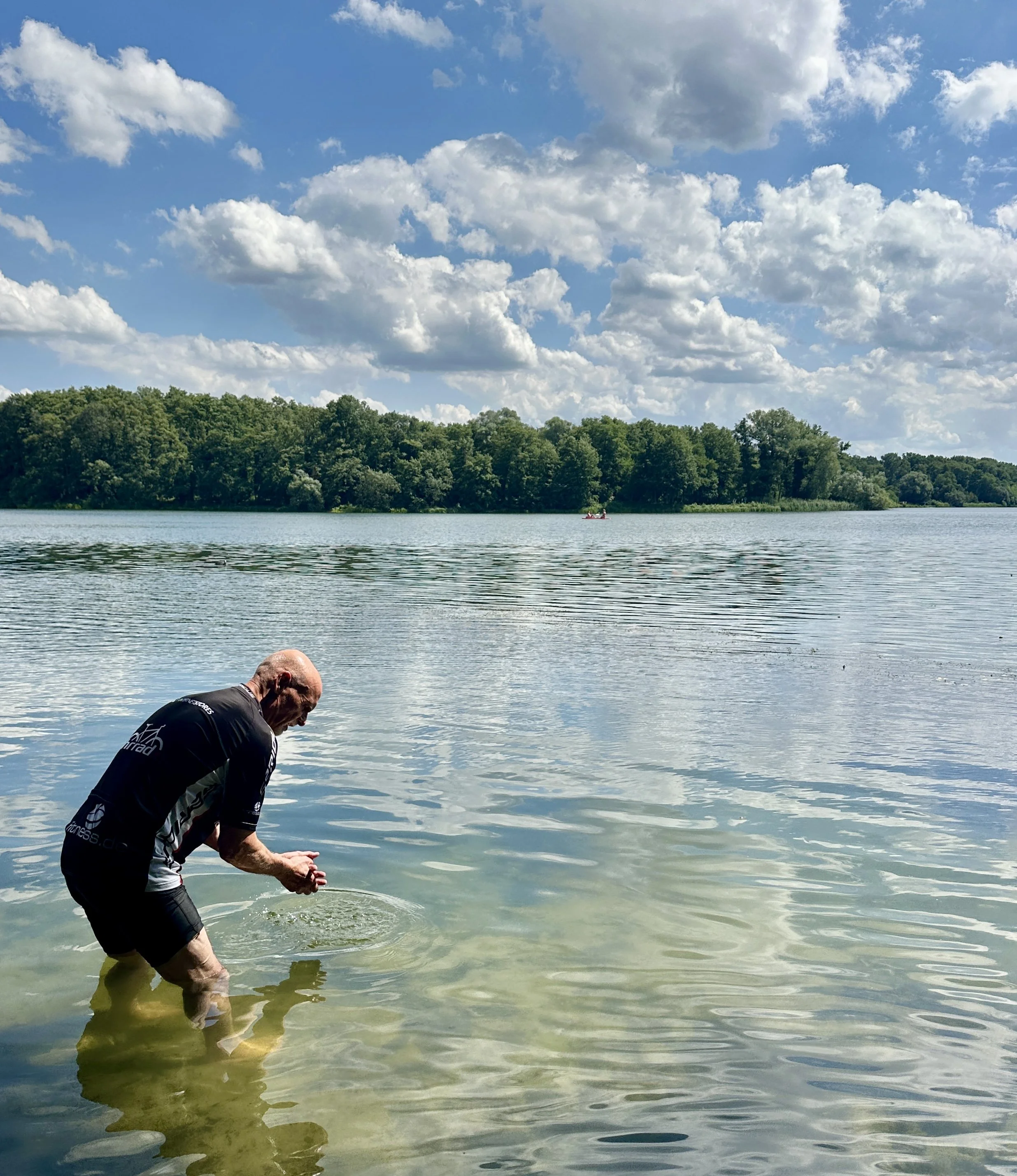 Berliner Mauerweg mit dem Fahrrad, Mann bis zu den Knien im Wasser stehend