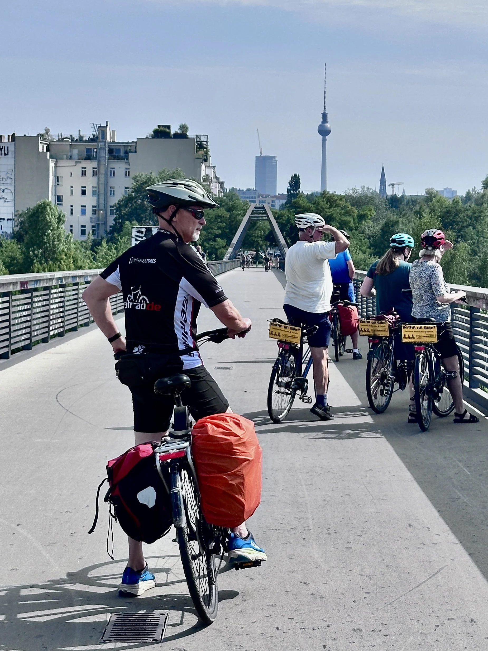 Berliner Mauerweg mit dem Fahrrad, Mann auf Brücke mit dem Fernsehturm aus Berlin im Hintergrund