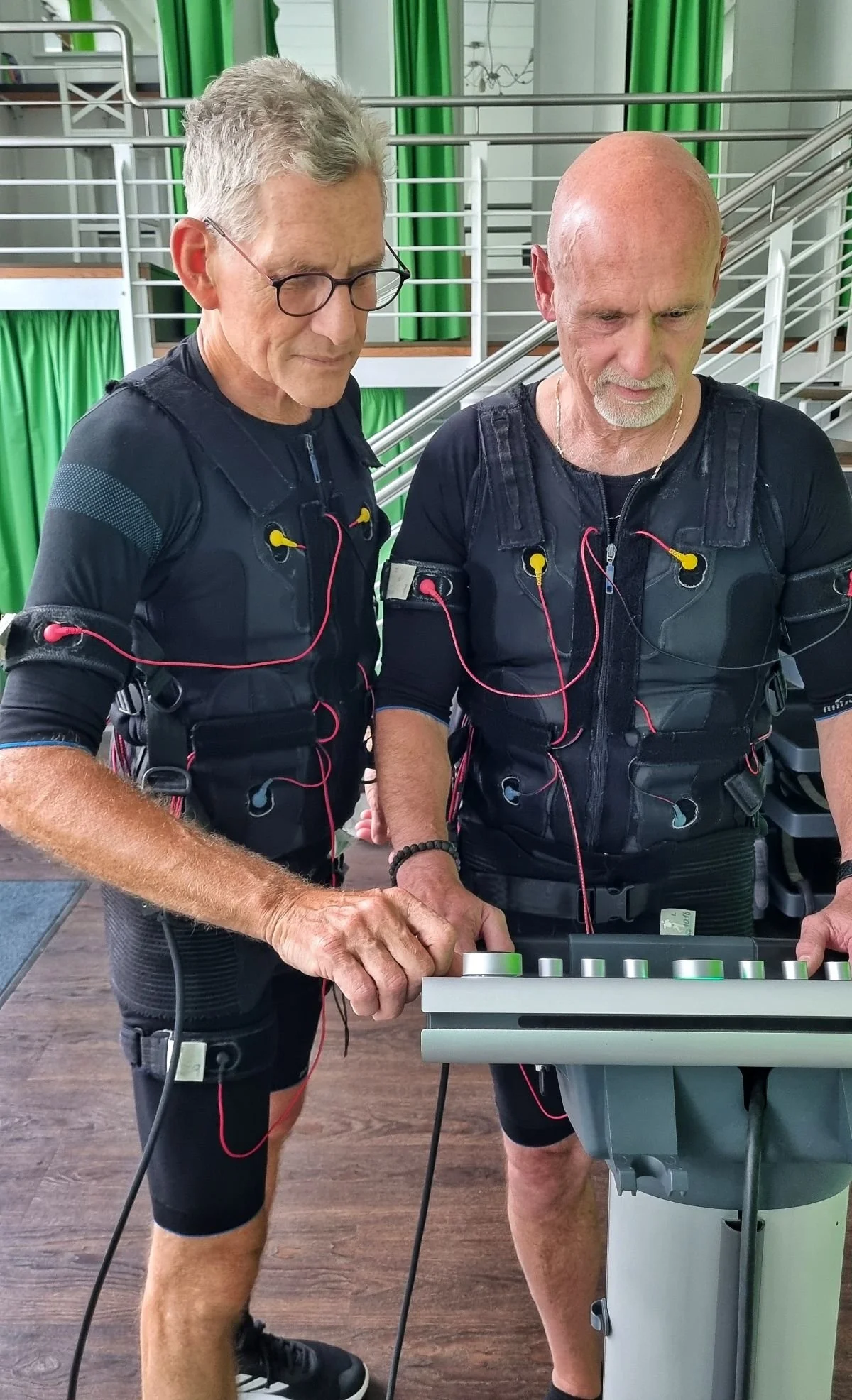 2 Männer schauen auf Schaltpult beim EMS-Training, Bewegung im Alltag