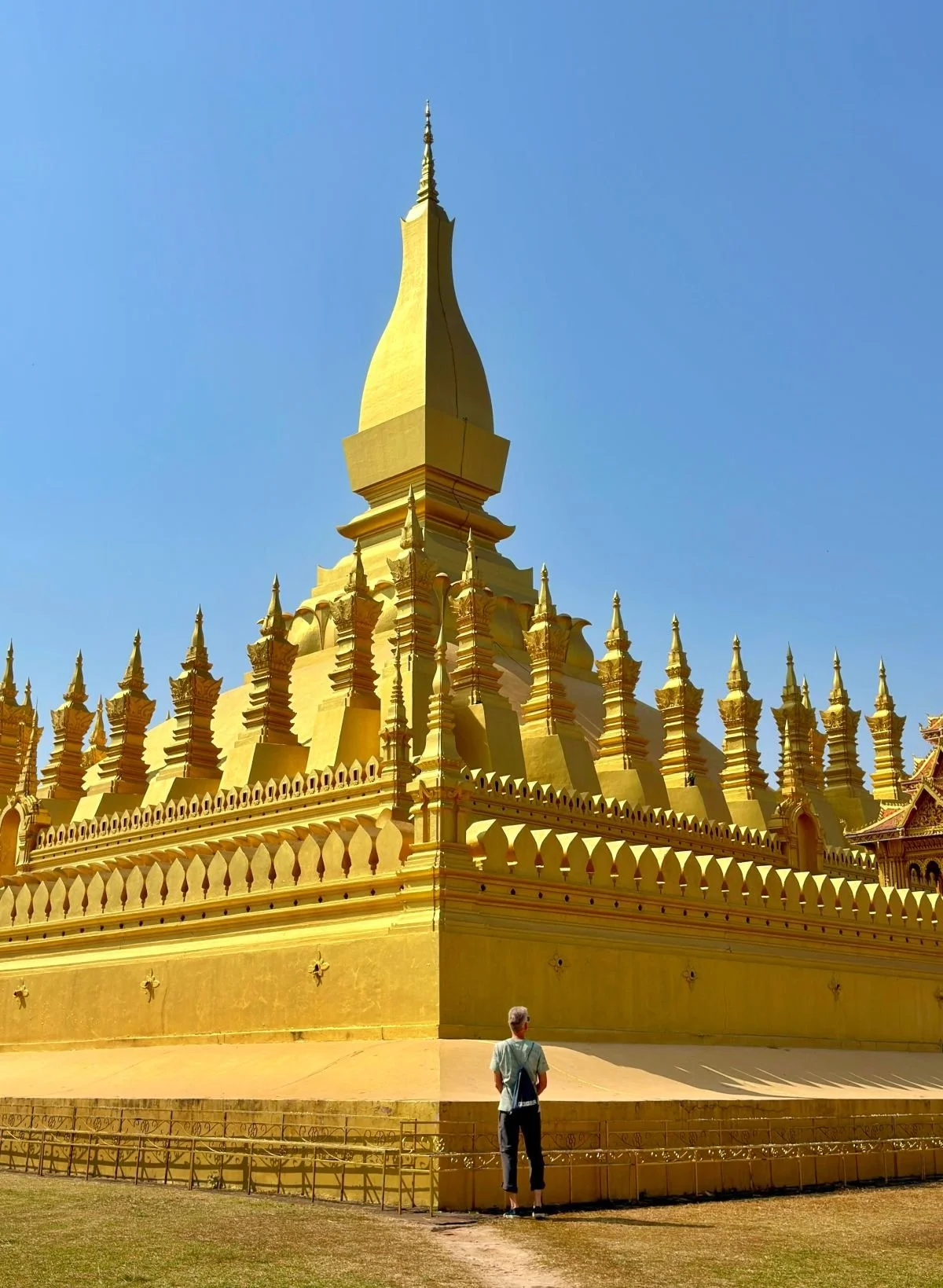 Laos - Rundreise auf eigene Faust - Mann steht vor dem goldfarbenen Pha That Luang