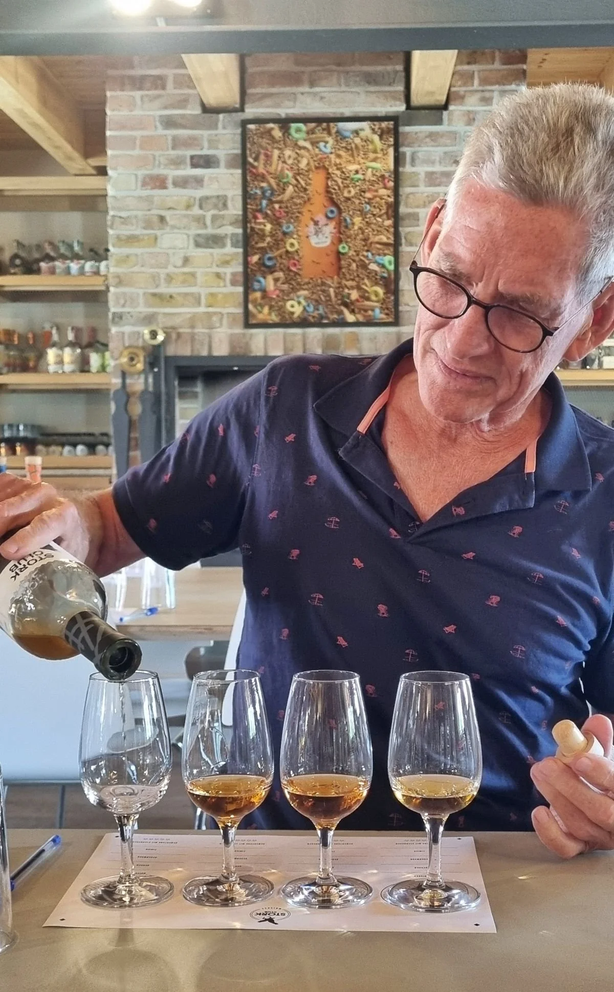 Mann gießt sich Whiskeyprobe in eins von vier Gläsern ein -Ausflugsziel Brandenburg - Stork-Whiskey-Brennerei
