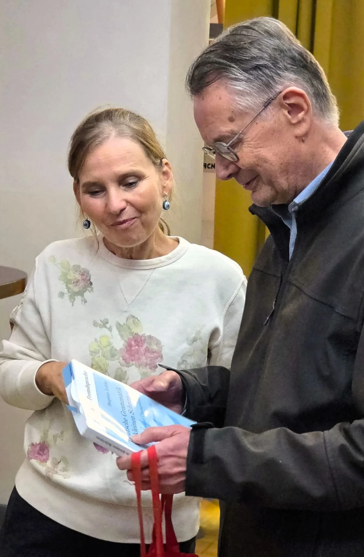 Ehrenamt für Senioren Berlin - Frau und Senior betrachten ein Grammatikbuch im Sprachcafé Mistéchko