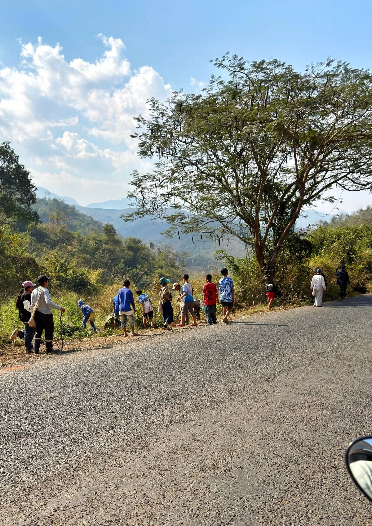 Laos - Rundreise auf eigene Faust - Menschen beim reinigen einer Landstraße bei Luang Prabang