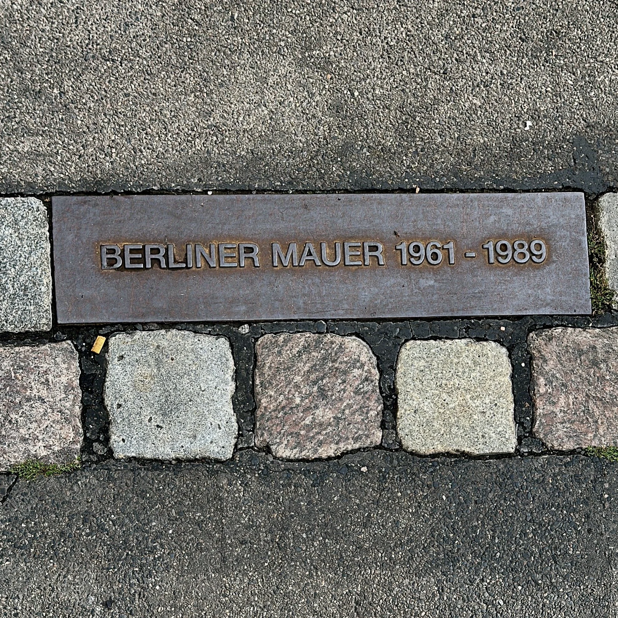 Berliner Mauerweg mit dem Fahrrad, gepflasterter Mauerverlauf mit Tafel