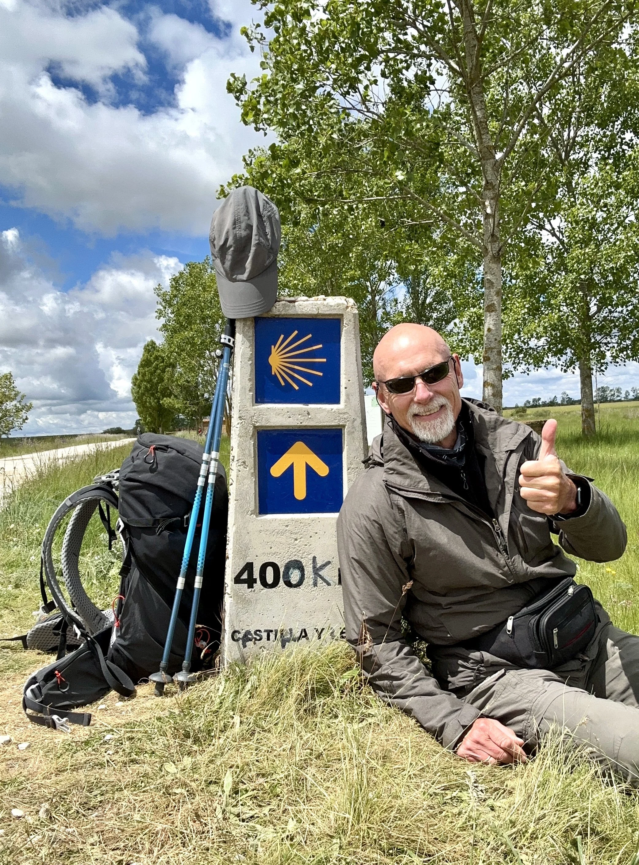 Camino Francés, Mann an einem Kilometerstein sitzend