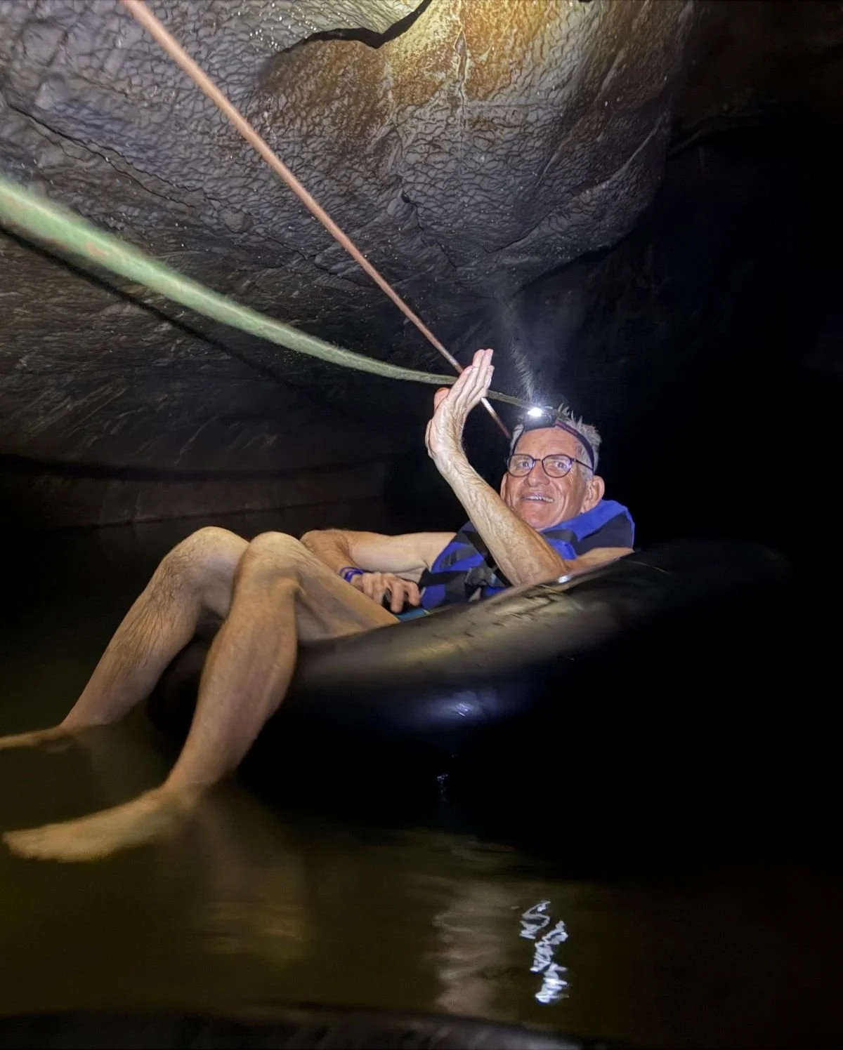 Laos - Rundreise auf eigene Faust - Mann schwimmt im Reifenschlauch durch Höhle