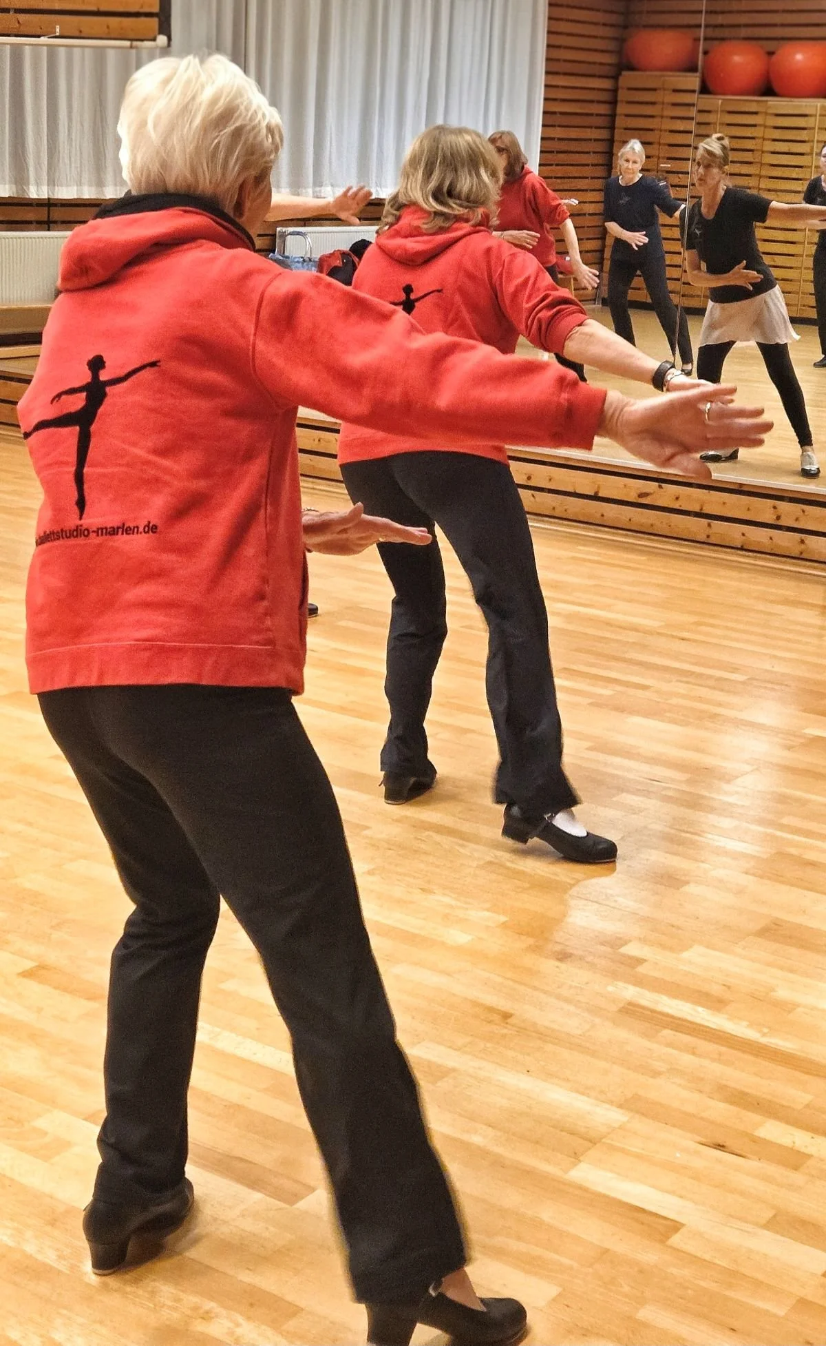 stepptanz für senioren berlin - Seniorinnen im roten Hoody üben Steppschritte vor dem Spiegel