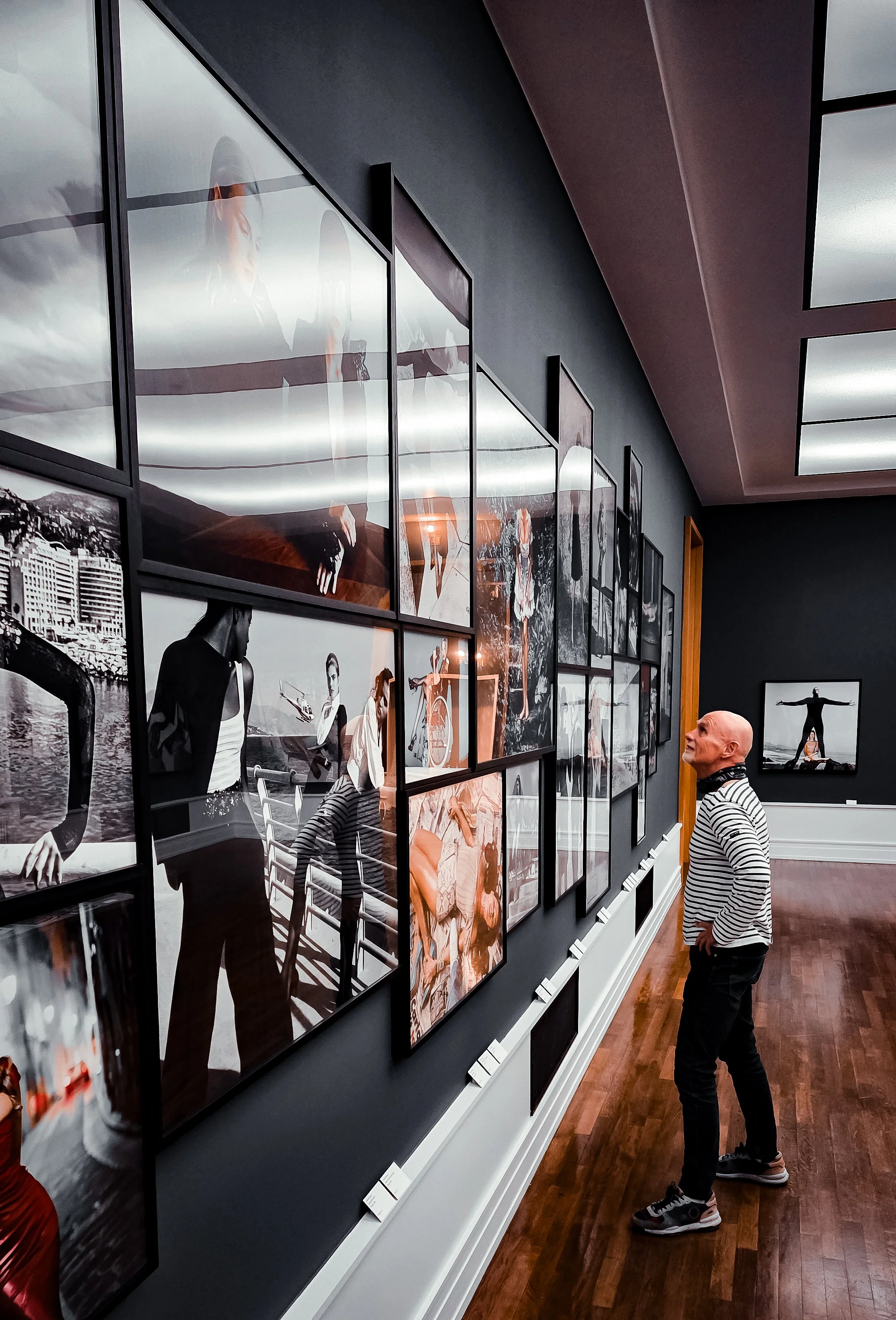 Fotos von Helmut Newton im Museum, Mann vor einer Wand stehend mit vielen Fotos