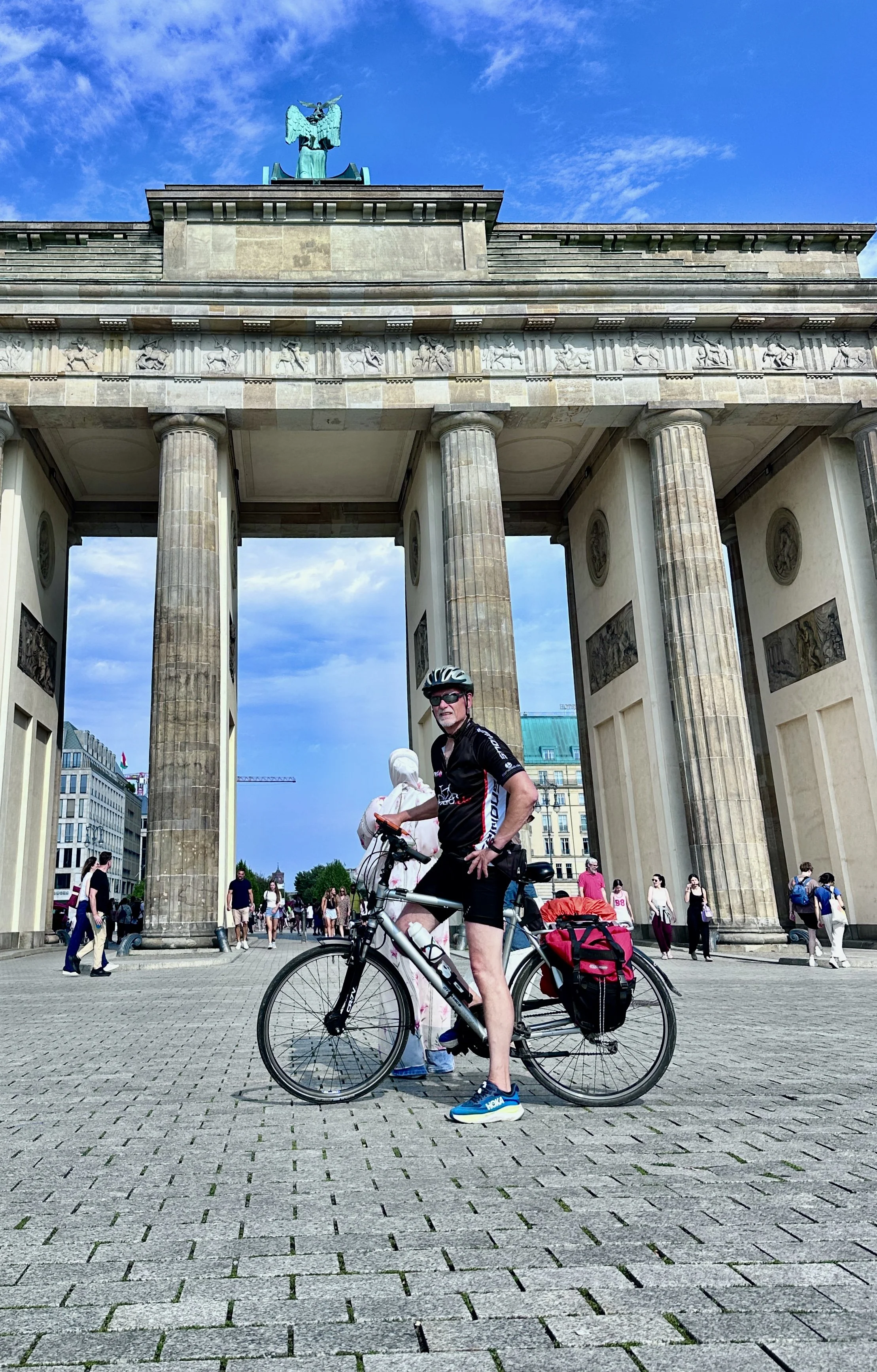 Berliner Mauerweg mit dem Fahrrad, Mann mit Fahrrad vor dem Brandenburger Tor