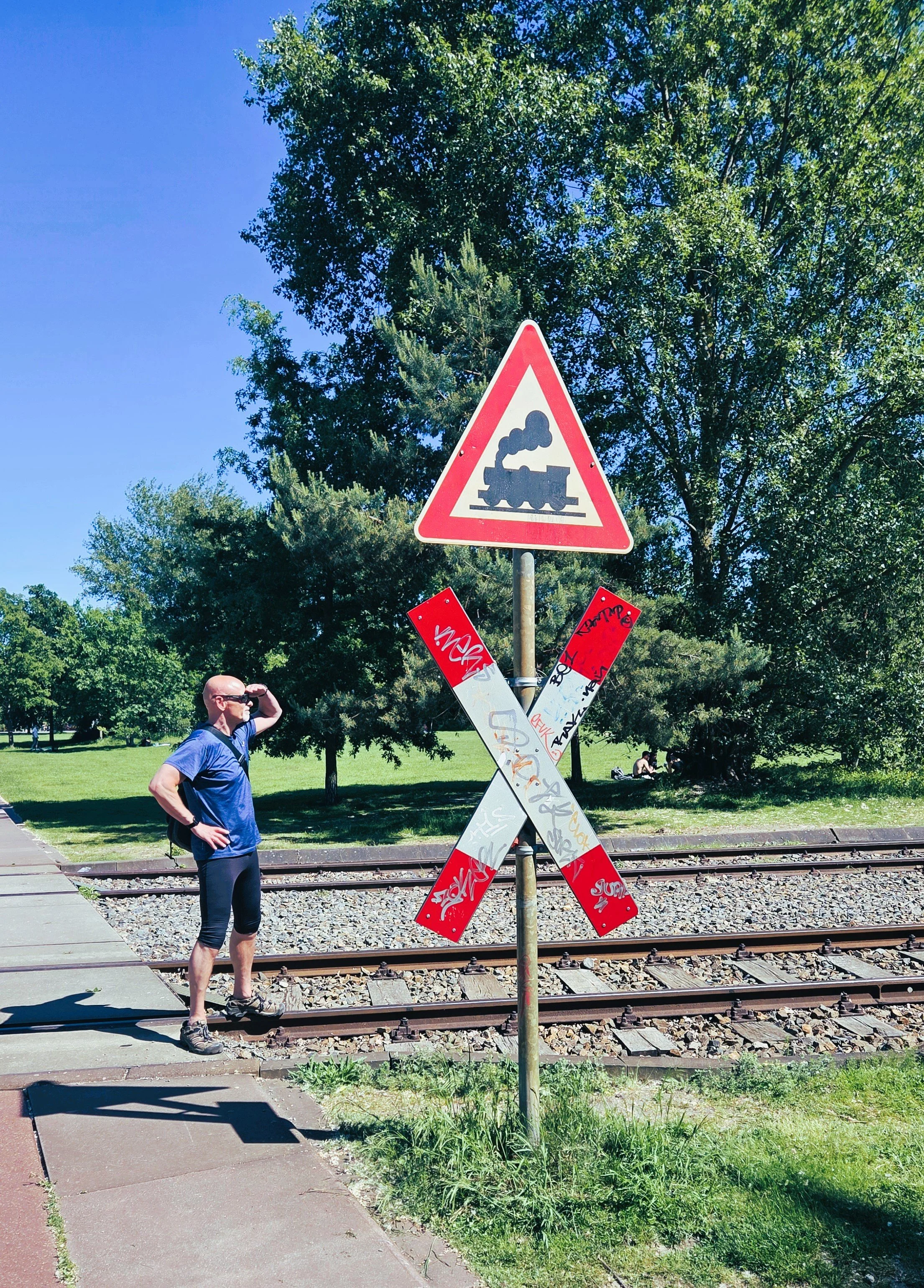 Auf dem Rad im Park am Gleisdreieck – die schönsten Parks in Berlin, Andreaskreuz mit Mann in die Ferne blickend
