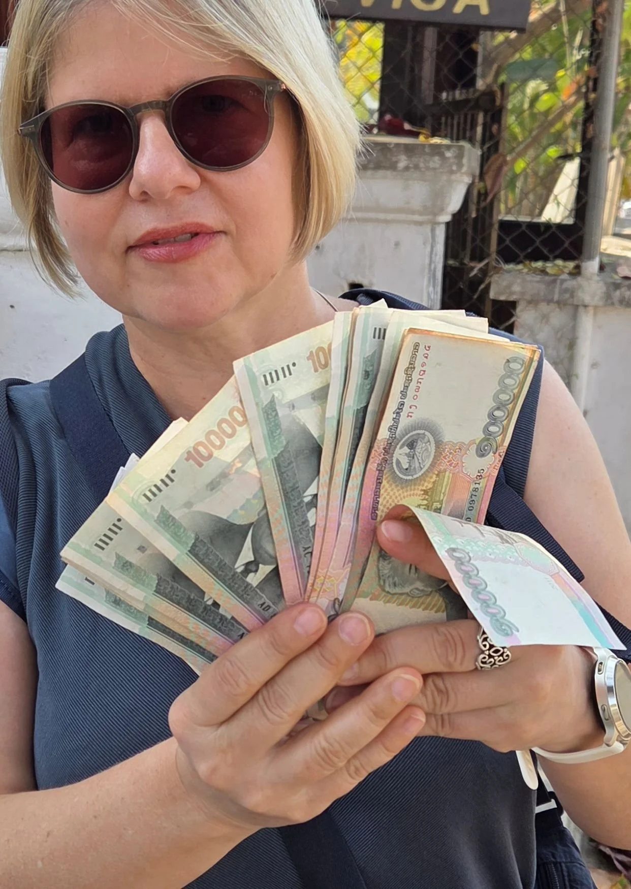 Frau hält ein Bündel Geldscheine, Laotische Kip, in der Hand, Rundreise Laos auf eigene Faust