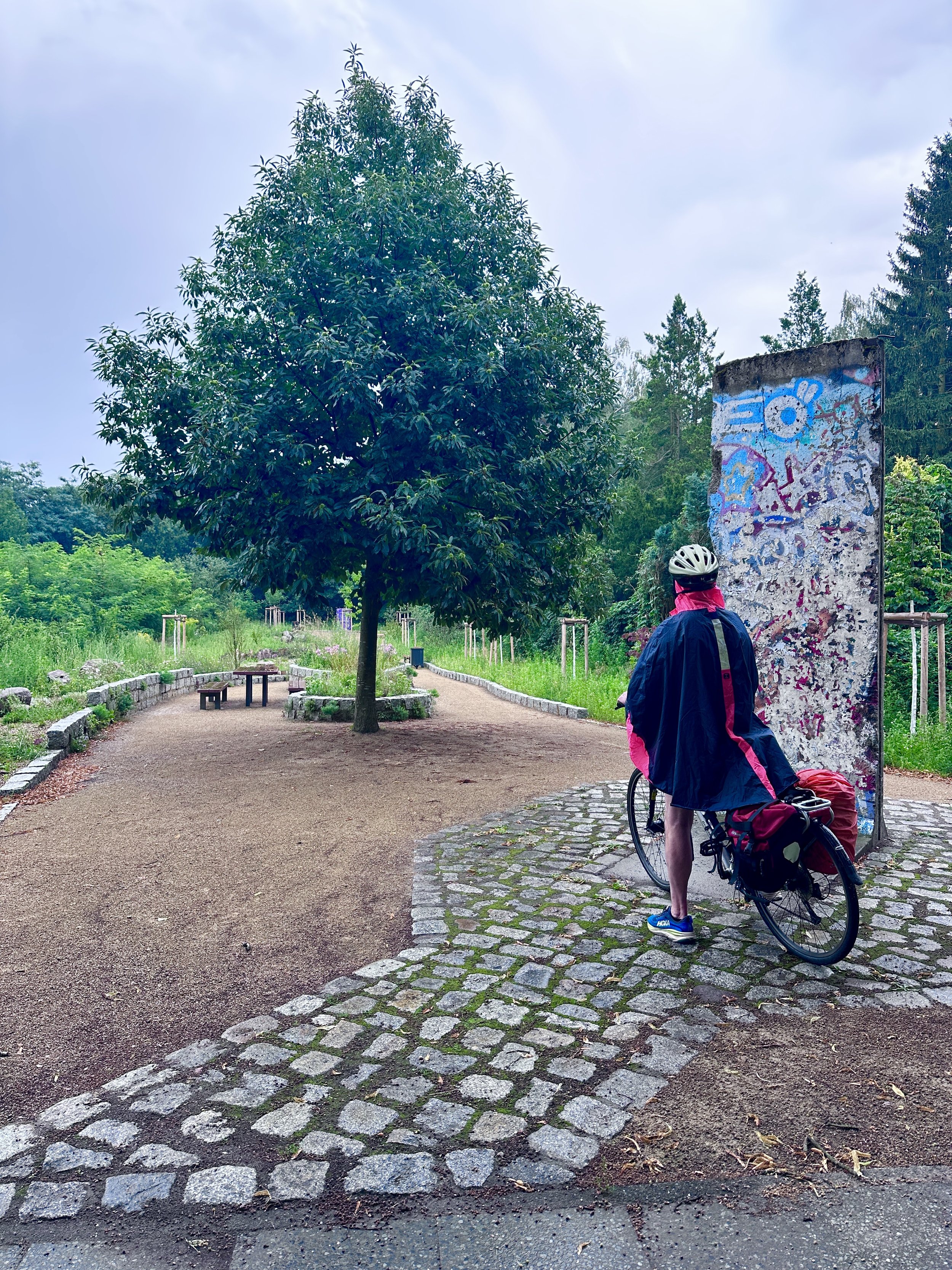Berliner Mauerweg mit dem Fahrrad, Mauerrest mit Mann auf Fahrrad davor